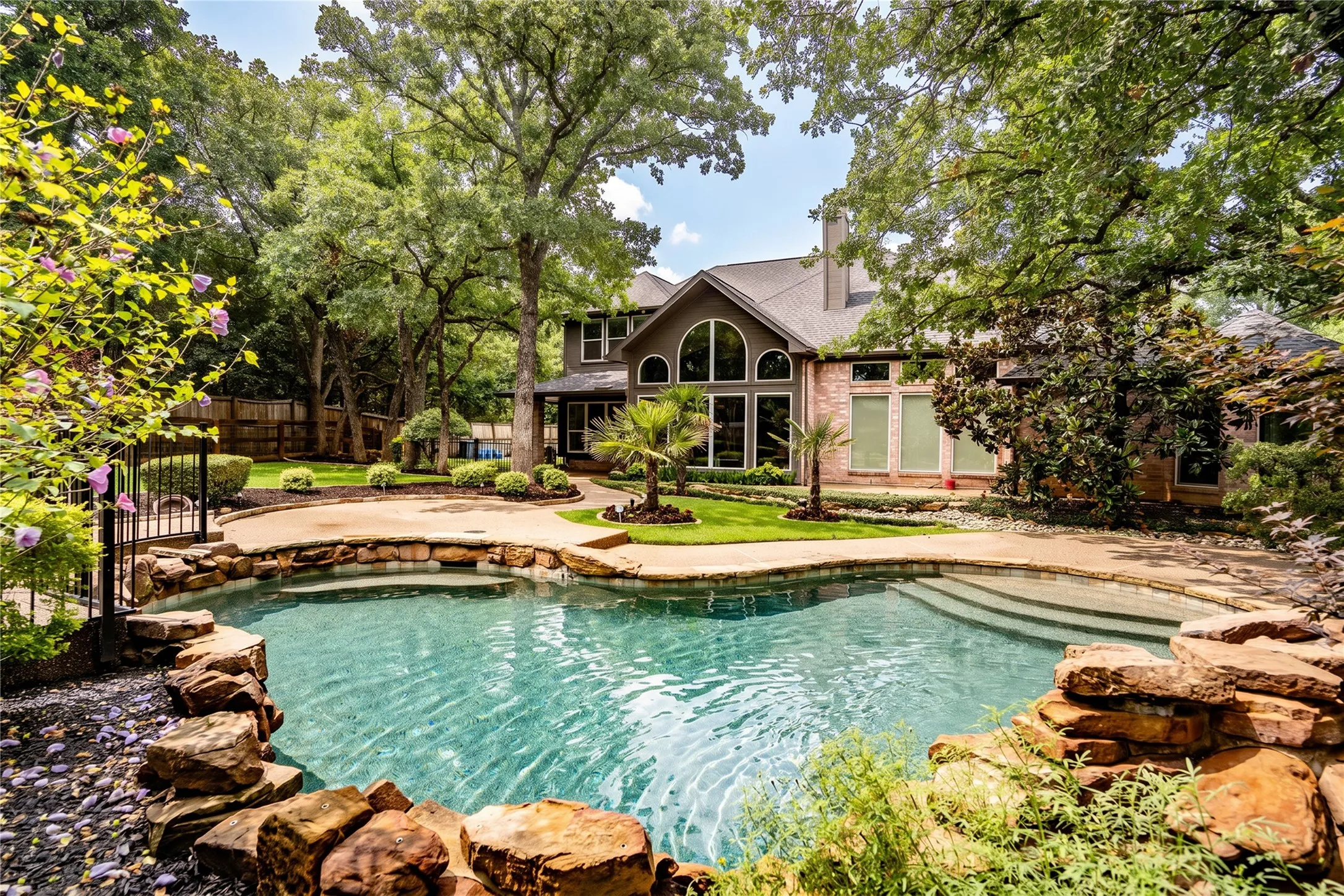 Expansive backyard oasis featuring a freeform swimming pool with rock coping and integrated steps