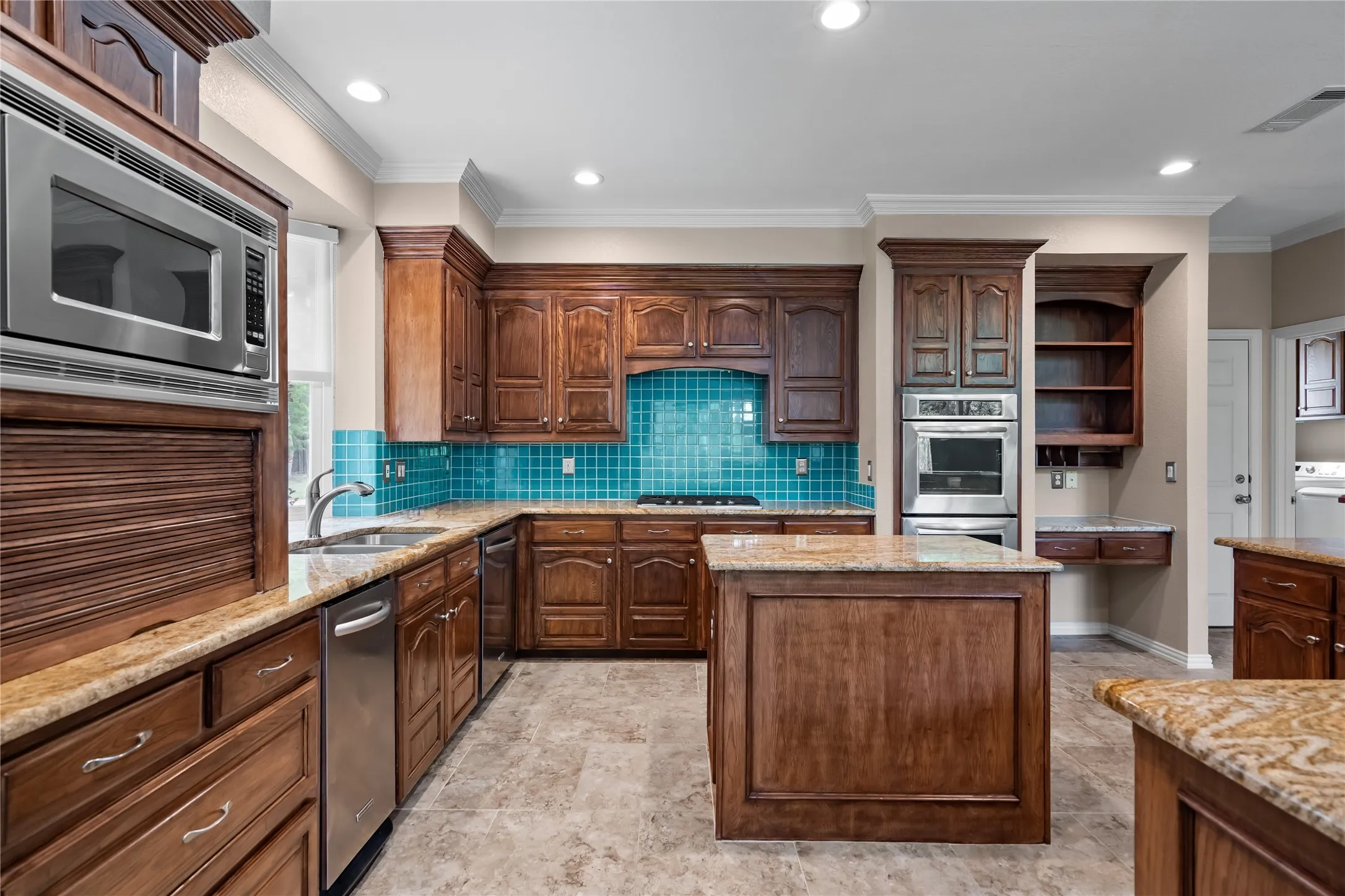Kitchen featuring wood cabinetry, stainless steel appliances, a central island, and a distinctive blue tile backsplash