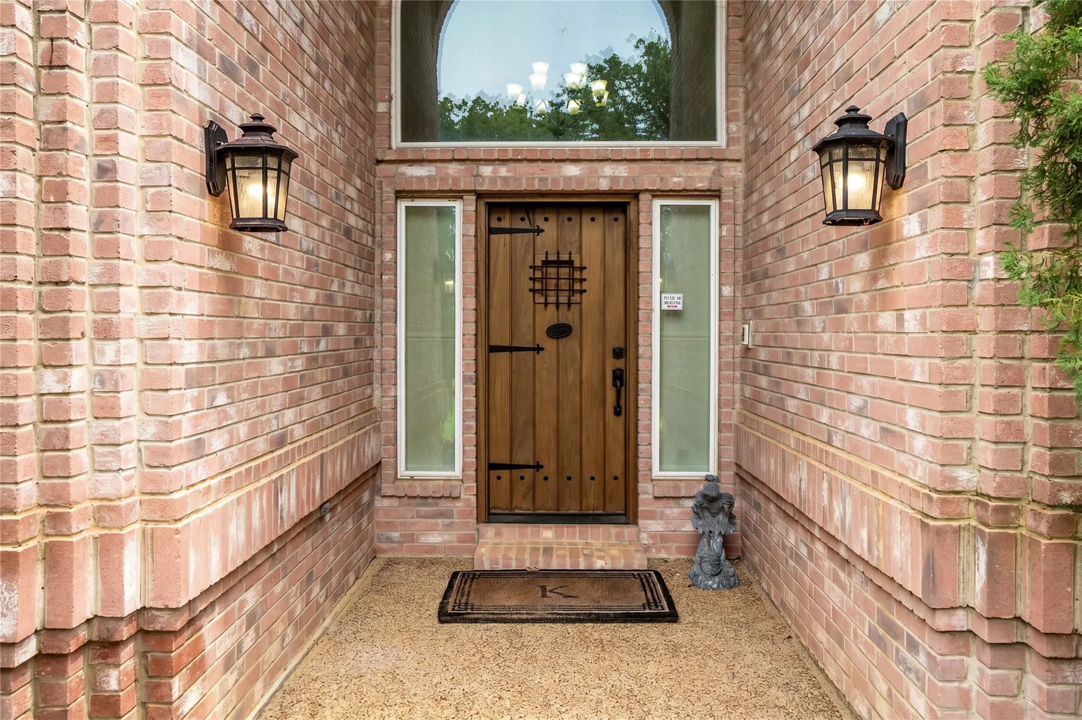 Brick exterior with a prominent arched transom window above a custom wood-panel entry door