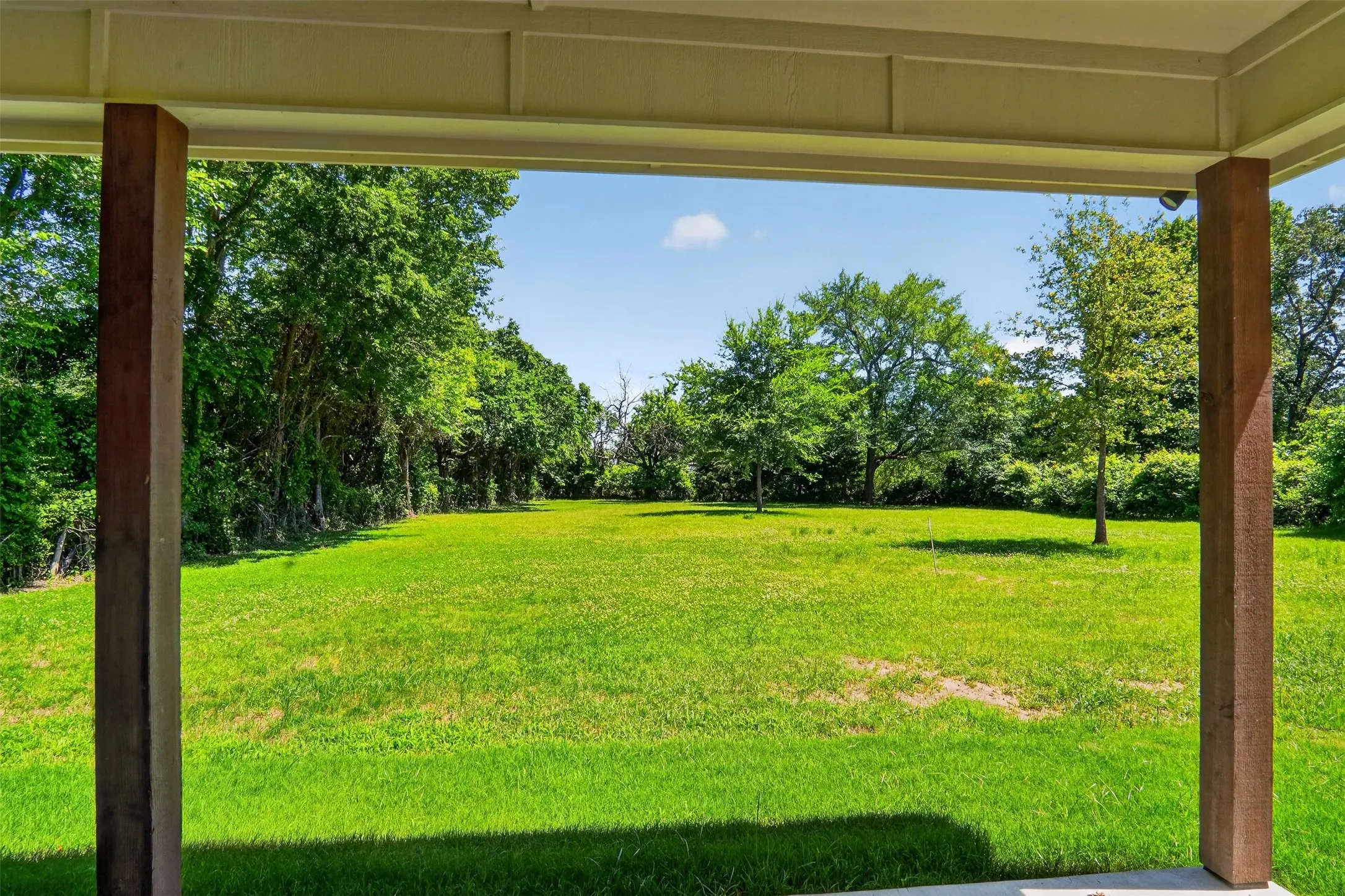 Expansive green lawn framed by mature trees, offering a significant outdoor space