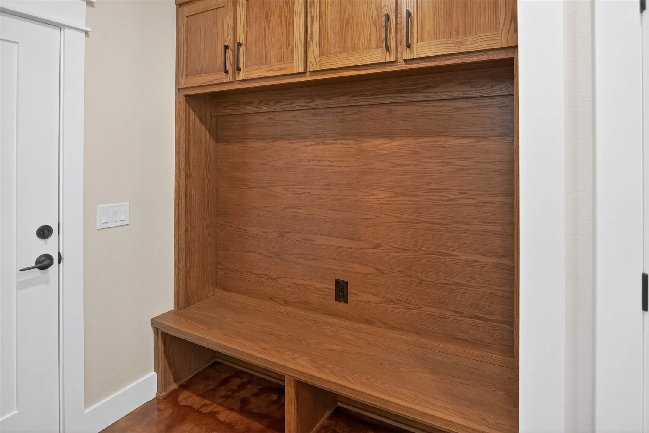 Built-in hall tree featuring wood-finish cabinetry with matte black hardware, integrated bench seating, and an open storage cubby
