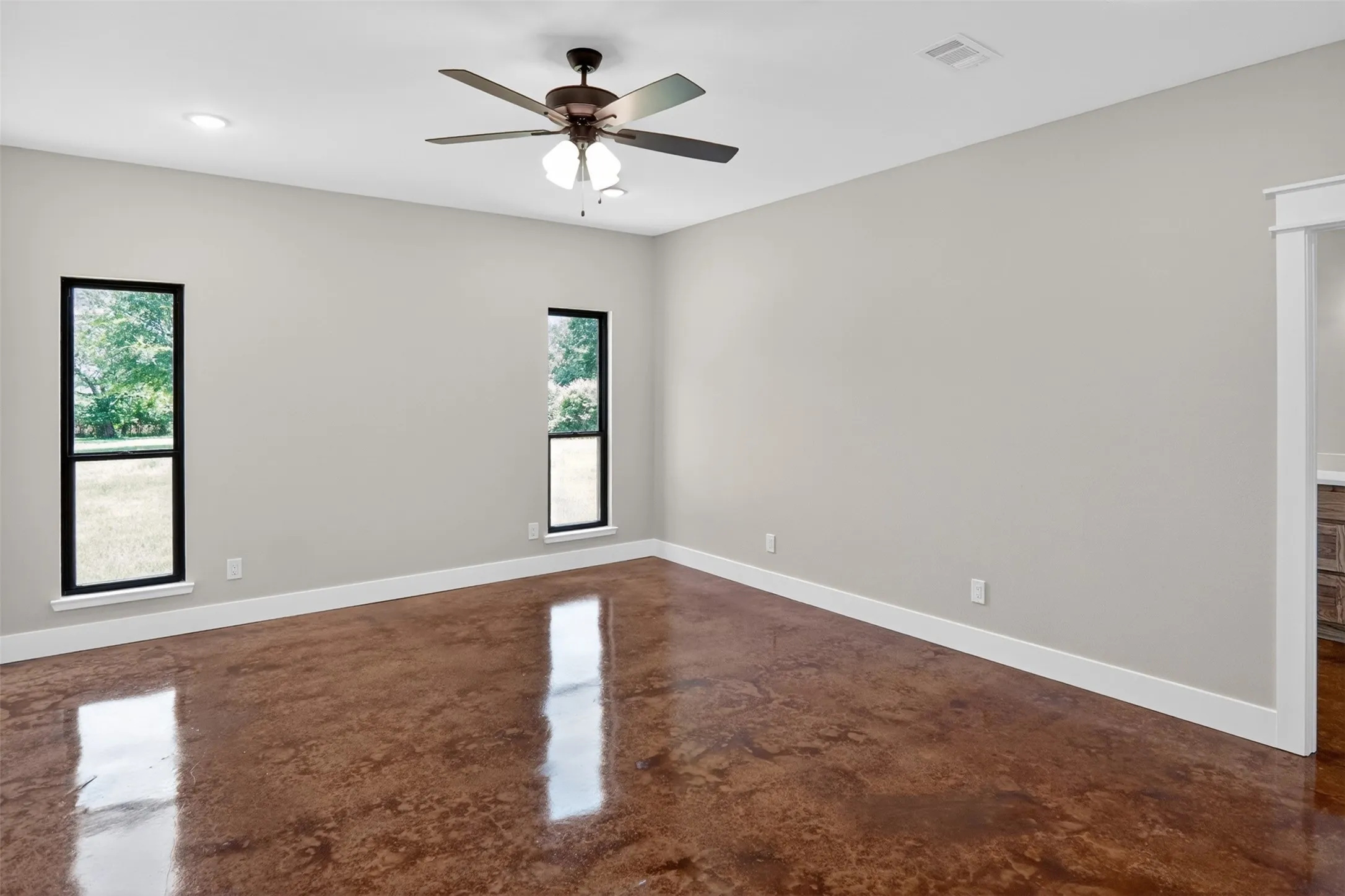 Primary Spacious room featuring polished concrete flooring, neutral wall tones, and white trim