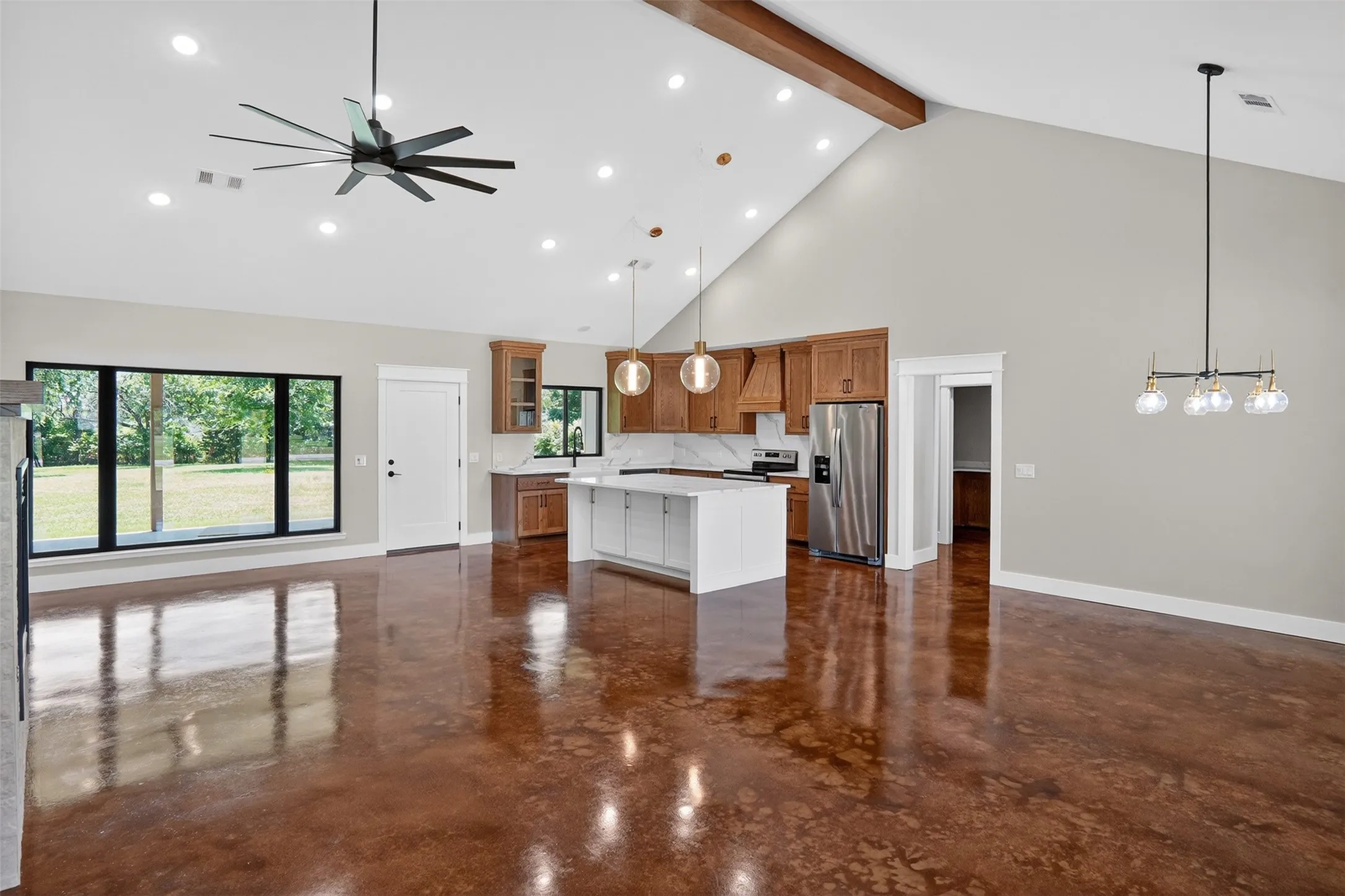 Open-concept living space featuring wood-finish flooring, a vaulted ceiling with exposed beam, and recessed lighting
