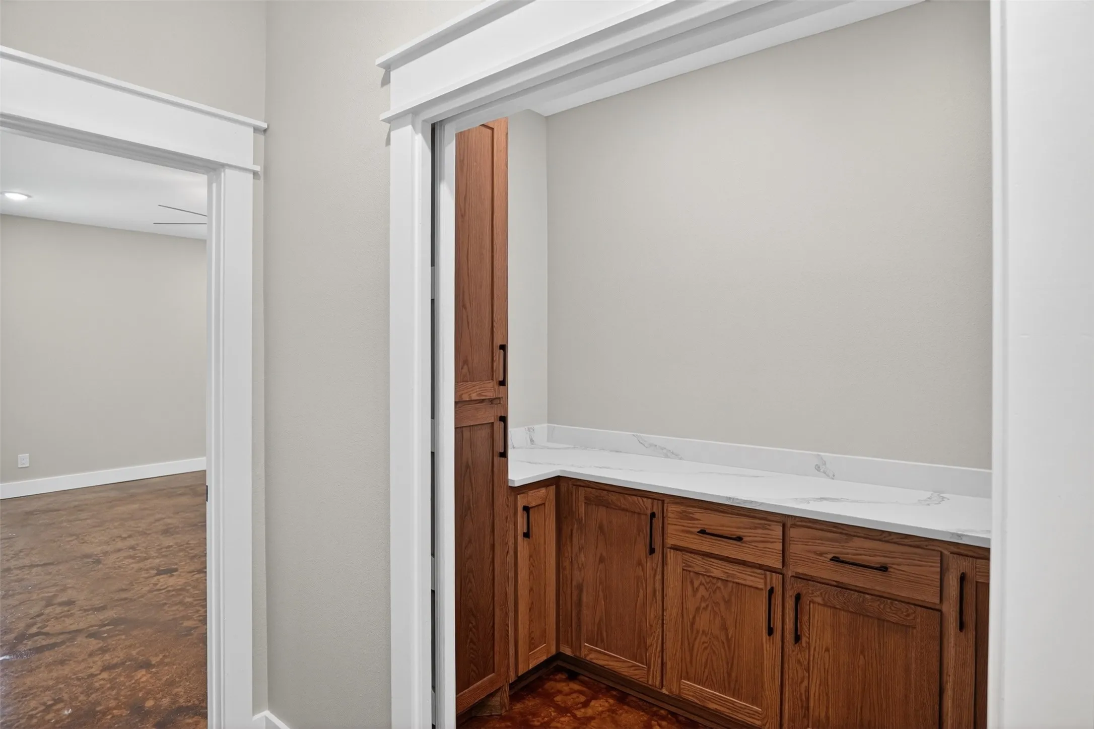 Built-in wood-finish cabinetry featuring black hardware, a white countertop, and a tall pantry cabinet