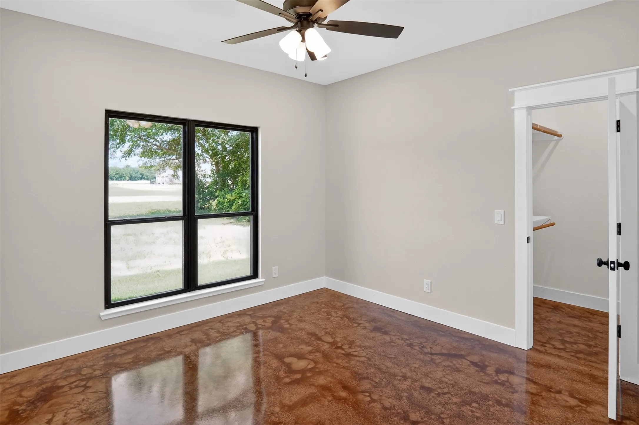 Room with polished concrete flooring, neutral wall paint, and white baseboards