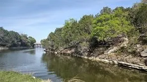 Waterfront property featuring a natural waterway, rocky shoreline, and mature trees