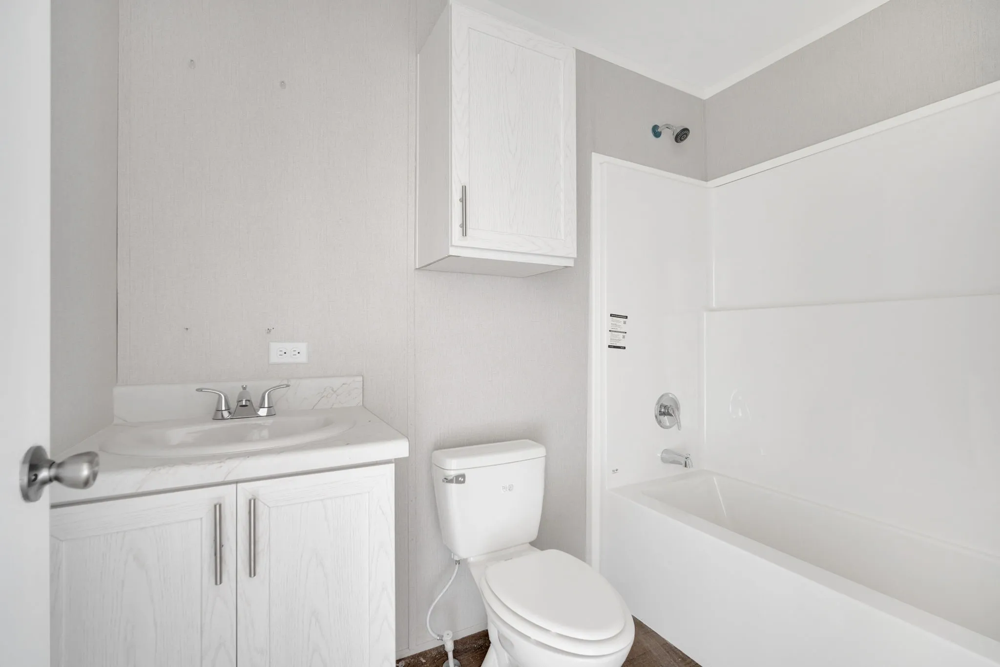 Bathroom featuring a white vanity with integrated sink, chrome faucet, white toilet, and a white tub with shower