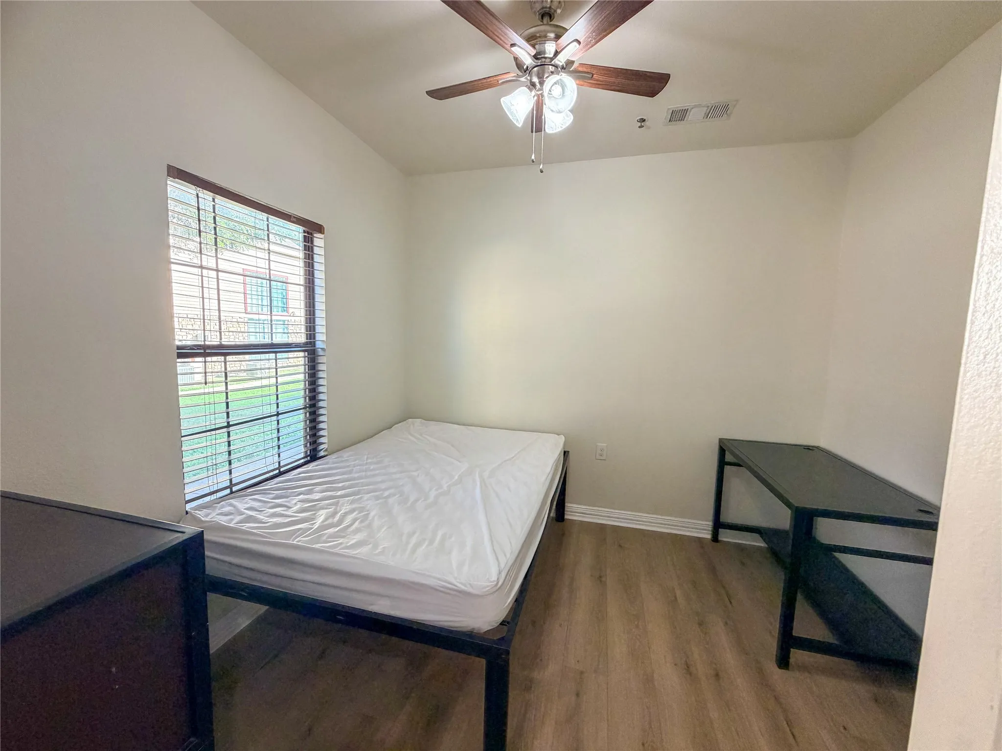 Wood-finish flooring, ceiling fan with integrated lighting, window with blinds, and neutral wall paint