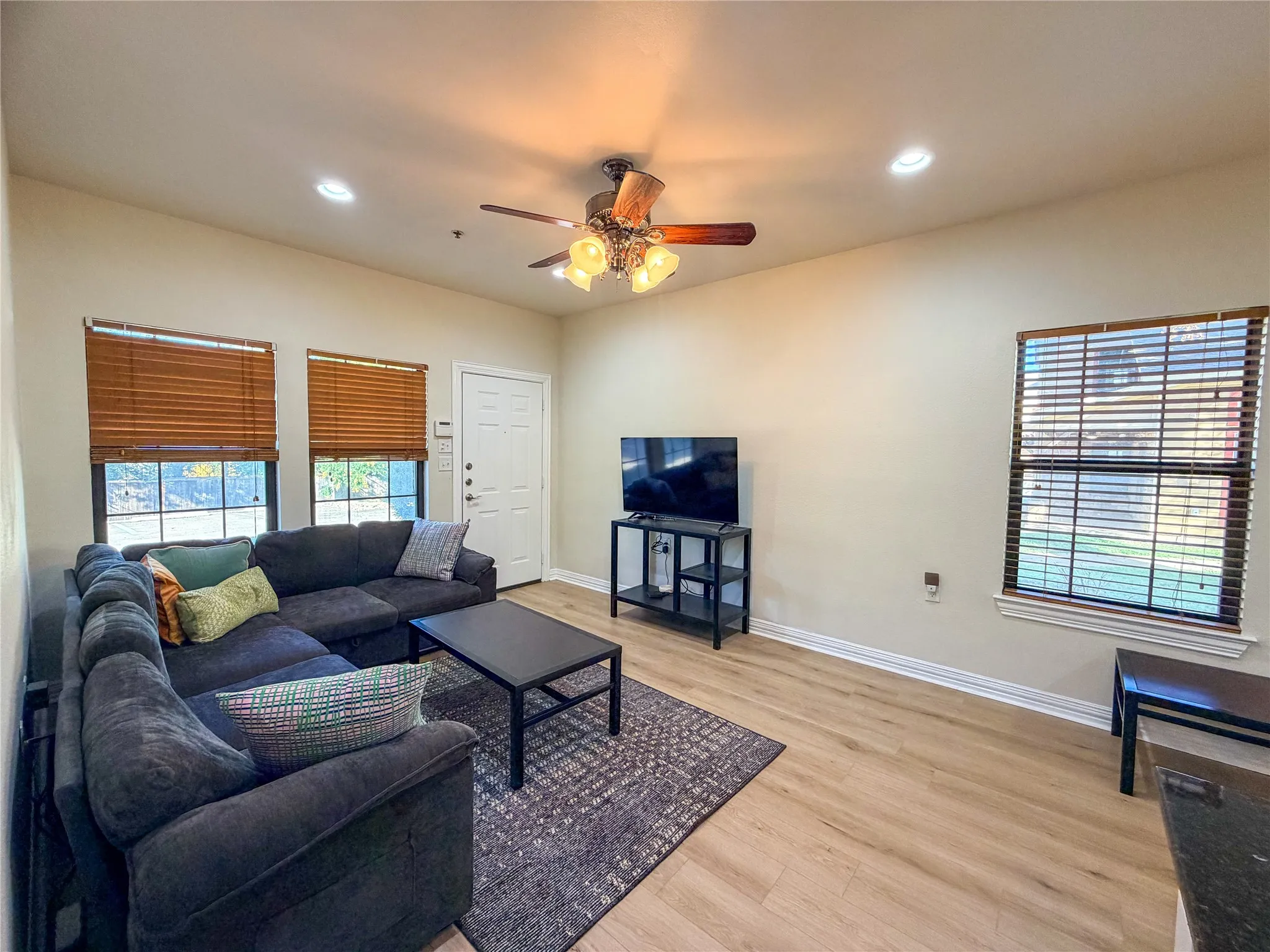 Recessed lighting, wood-finish flooring, ceiling fan, and multiple windows with blinds