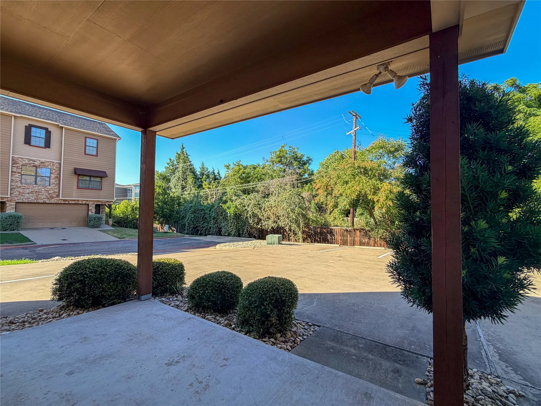 Covered patio with concrete flooring, accented by landscaped river rock beds and established shrubbery