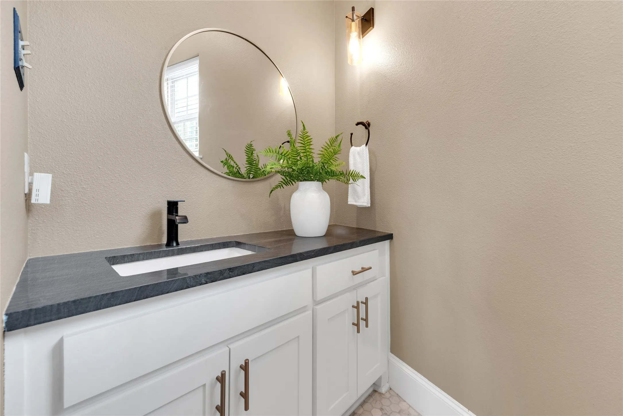 Vanity featuring a dark countertop, integrated rectangular sink, and matte black faucet