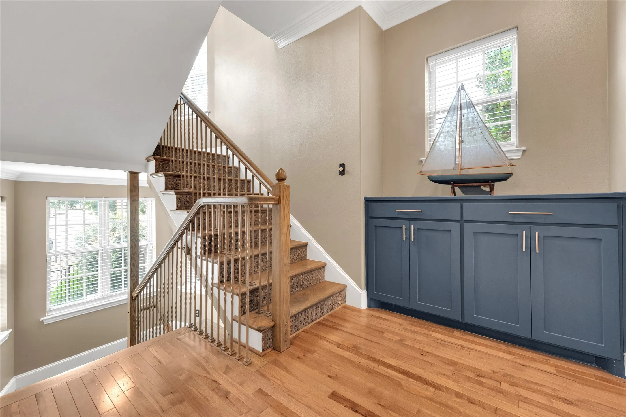 Hardwood flooring complements a staircase featuring wood newel posts, balusters, and carpeted treads