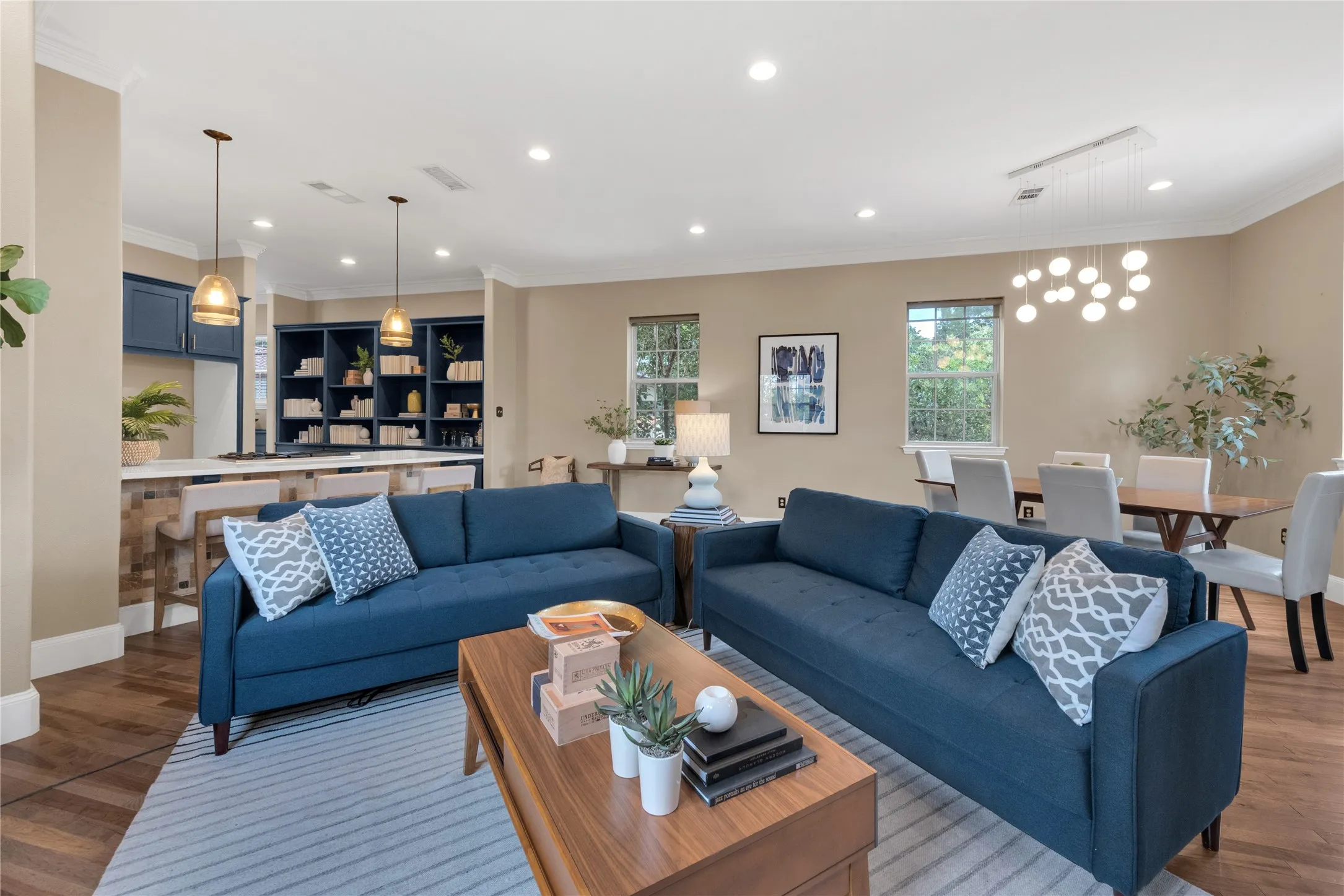Open-concept living space featuring wood-finish flooring, recessed lighting, and crown molding