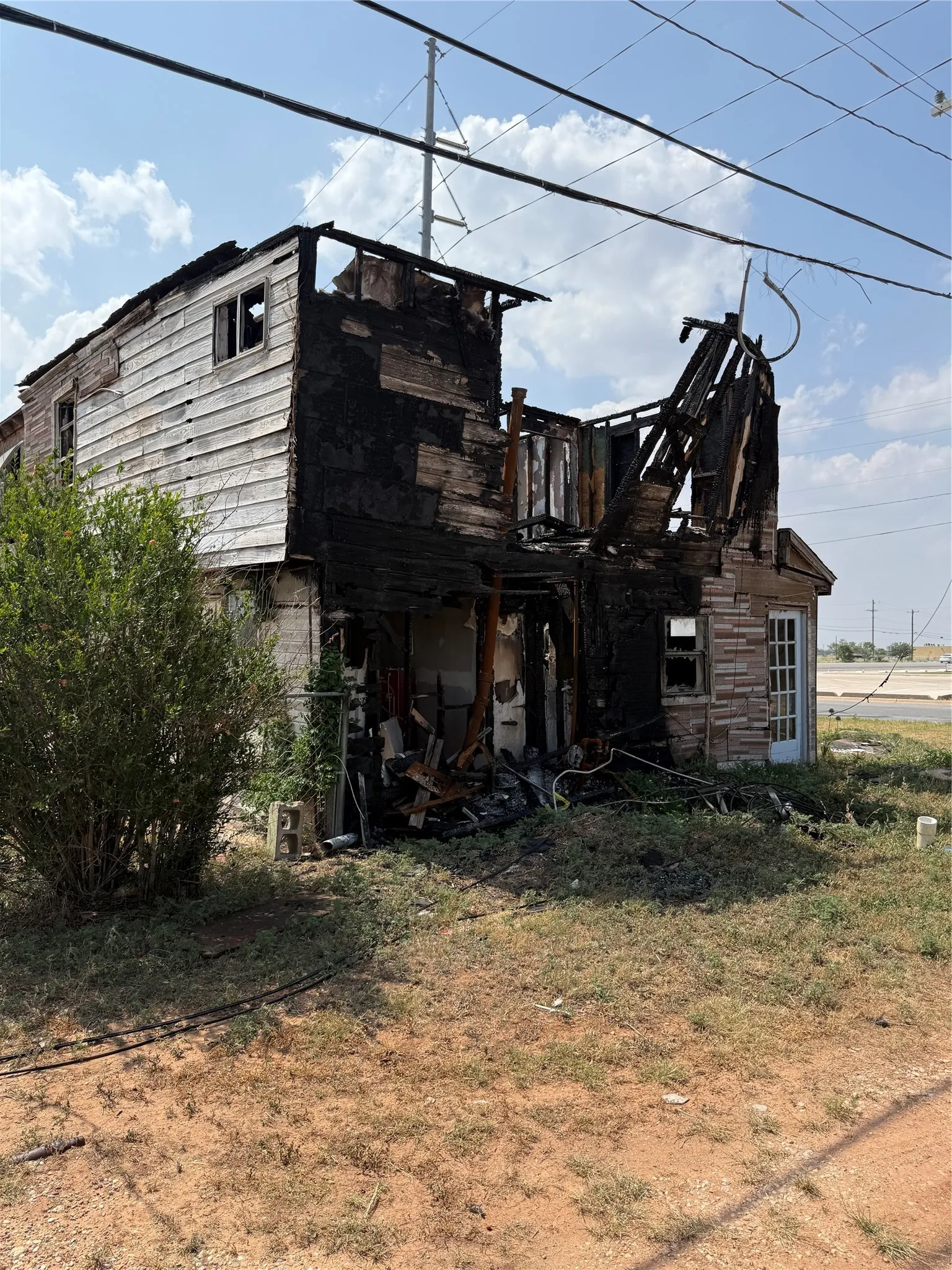 Existing structure featuring partial wood siding and a partially intact side door
