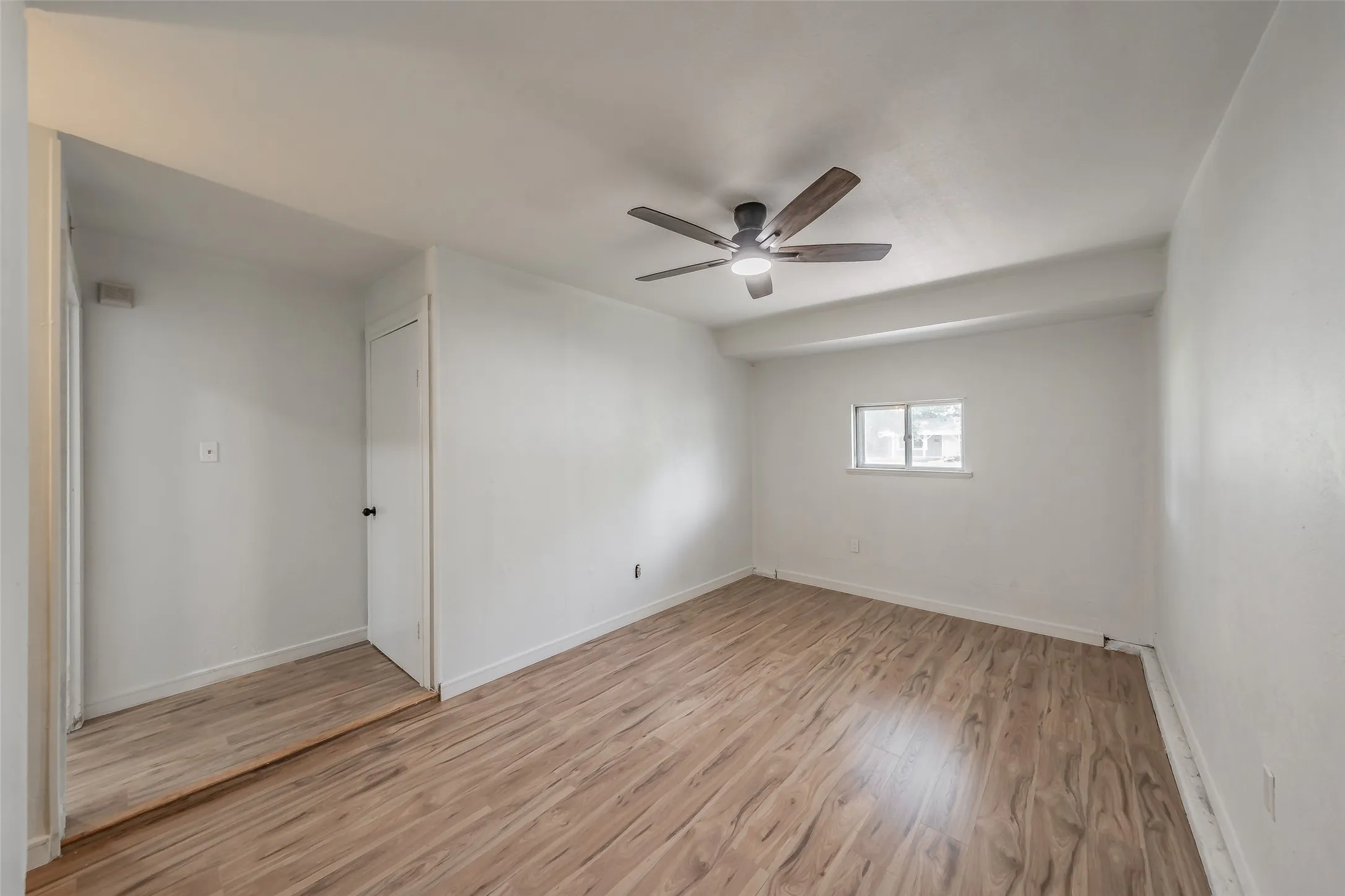 Room with wood-finish flooring, a window, and a ceiling fan with integrated lighting
