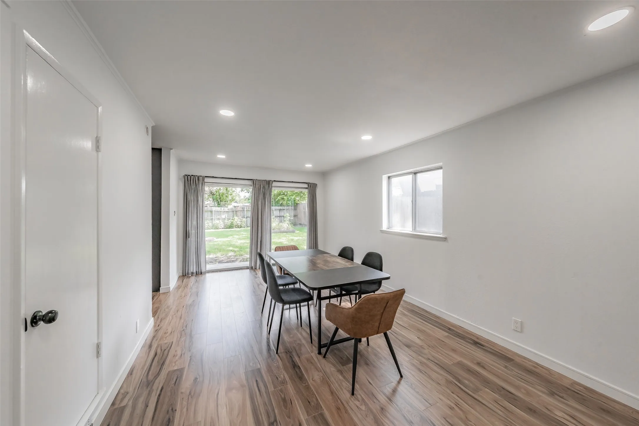 Spacious room featuring wood-finish flooring, white walls, and recessed lighting