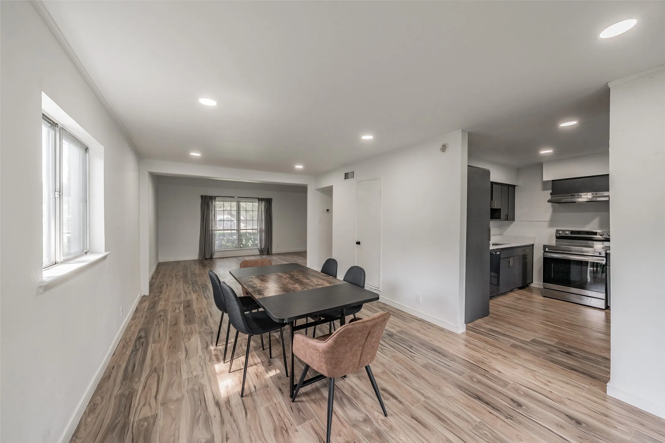Open-concept living space featuring wood-finish flooring, recessed lighting, and a kitchen with stainless steel appliances