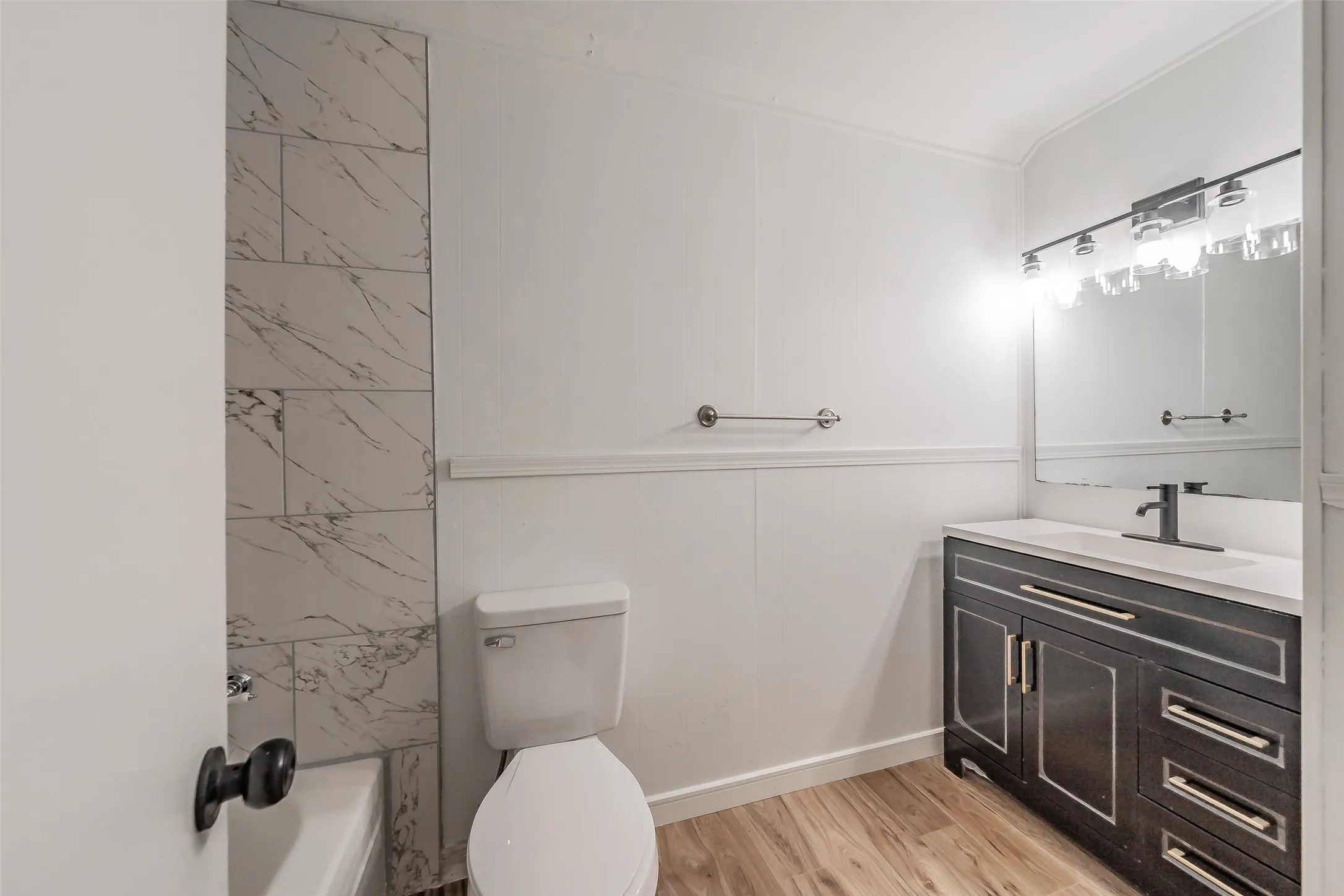 Bathroom featuring a dark wood-finish vanity with a white countertop, recessed sink, and black​​‌​​​​‌​​‌‌​‌‌​​​‌‌​‌​‌​‌​​​‌​​ faucet