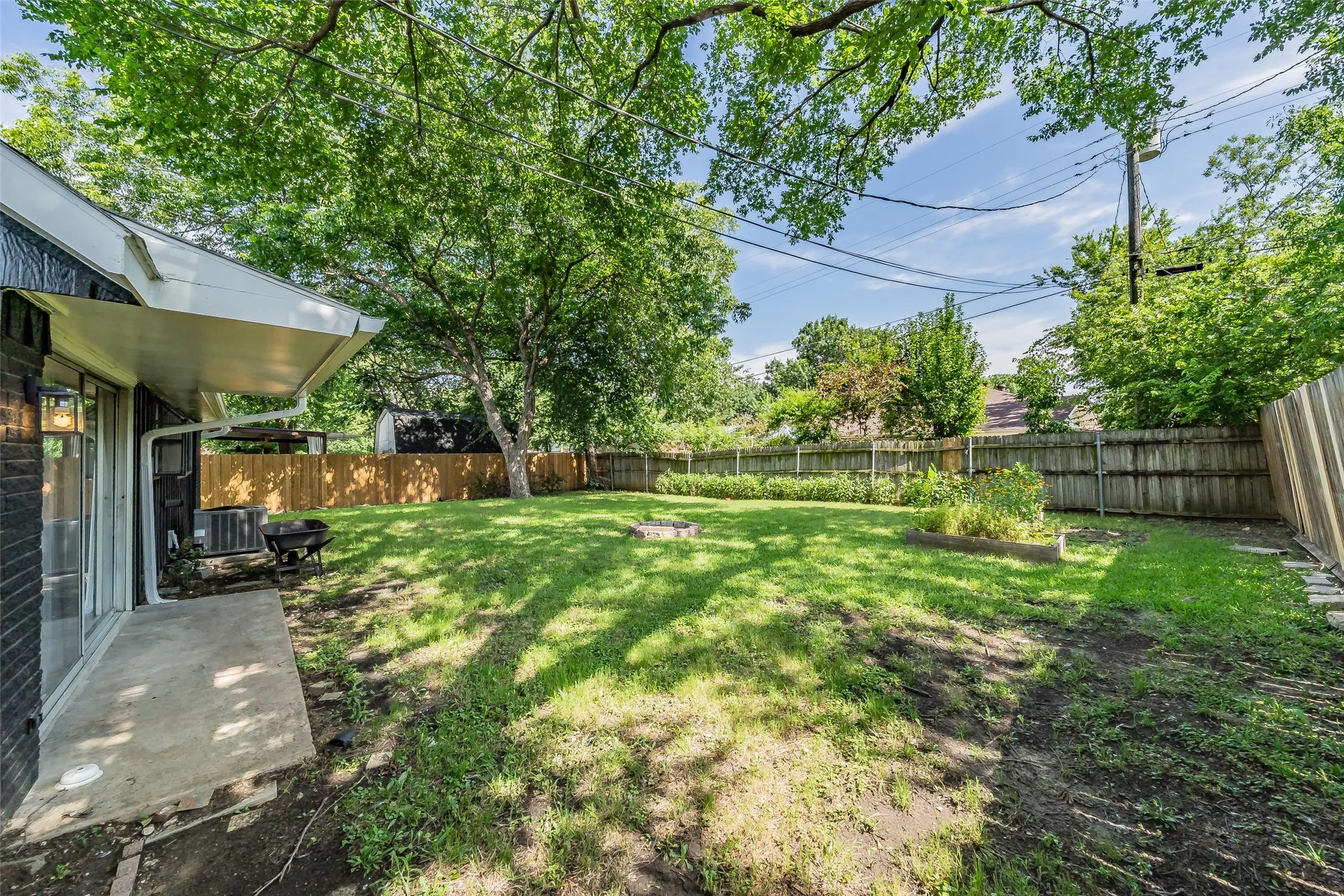 Expansive backyard featuring a manicured lawn, established trees, and a wooden privacy fence