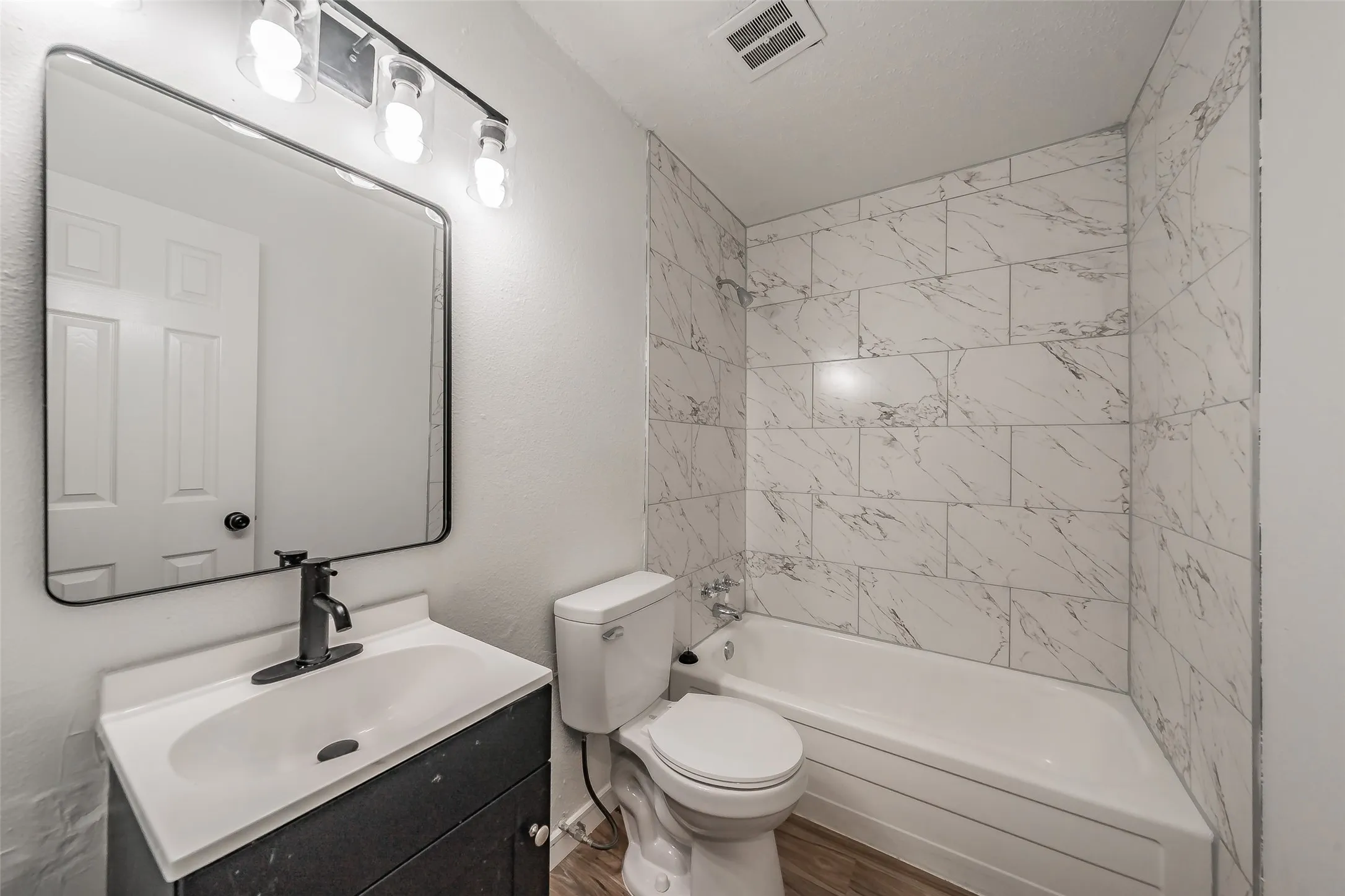Modern bathroom featuring a vanity with integrated sink, matte black faucet, and a large framed mirror