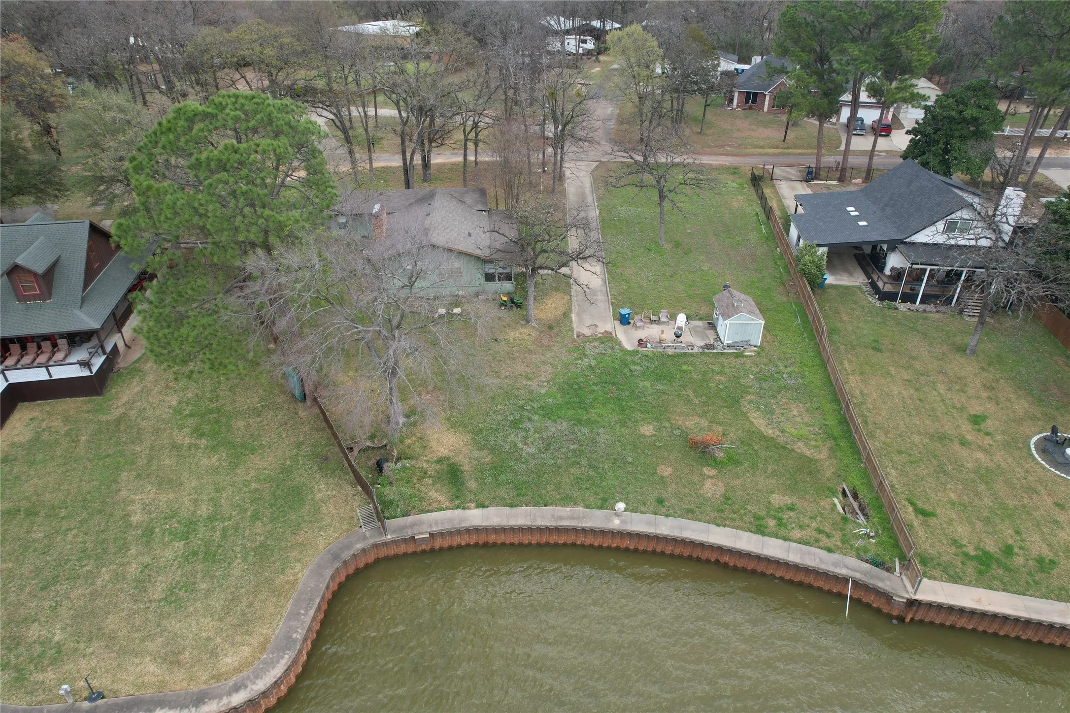 Waterfront property featuring a steel retaining wall, an old house-some say they would tear it down and build new, long driveway, storage, expansive green space, and mature trees