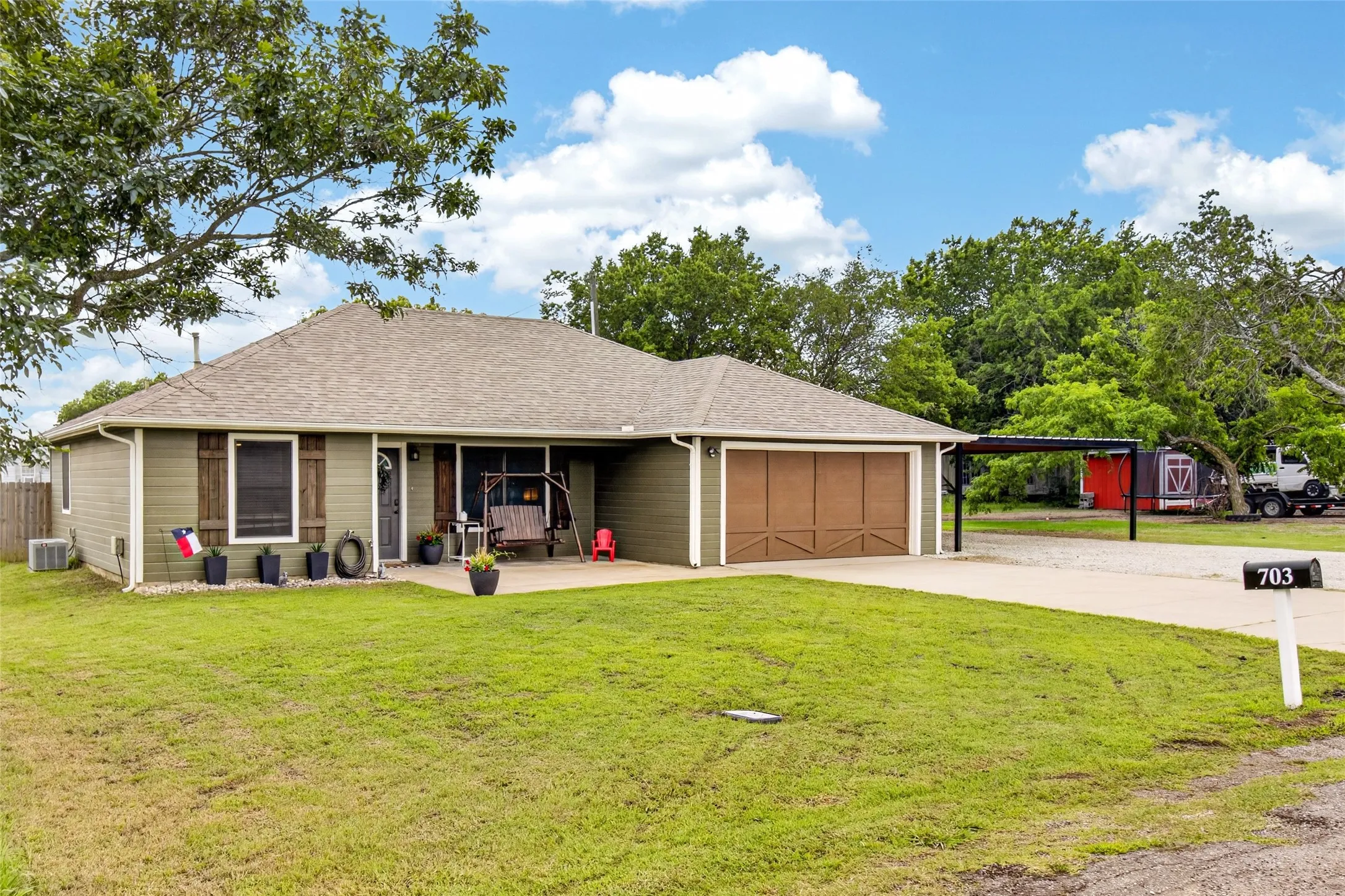 Ranch-style exterior with olive green siding, a light brown shingle roof, and a front concrete patio