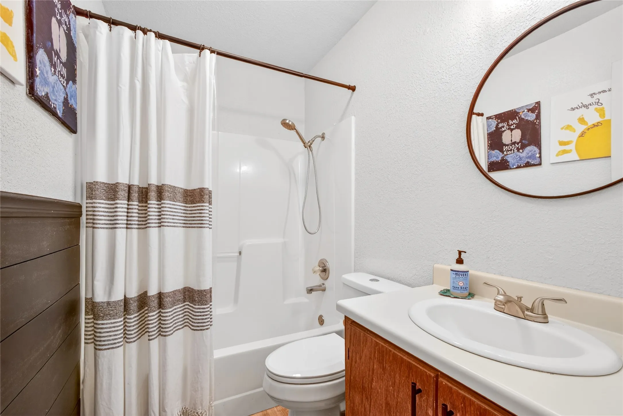 Bathroom featuring a white tub/shower combination with a handheld showerhead, a toilet, and a vanity with an integrated sink