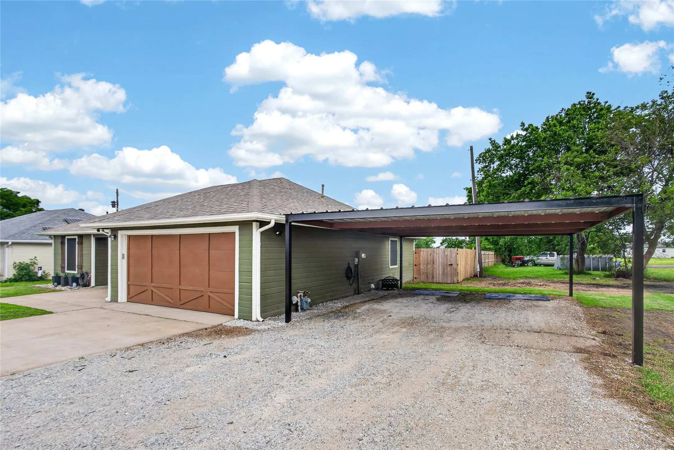 Exterior featuring olive green siding, a brown garage door with decorative trim, and a gray shingle roof