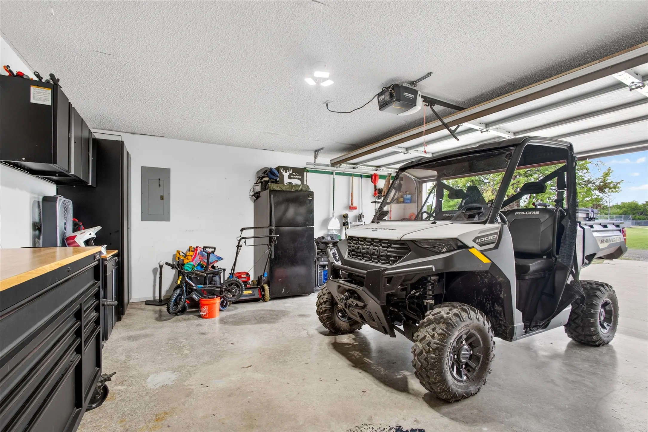 Garage featuring a concrete floor, built-in black cabinetry, and a butcher block countertop