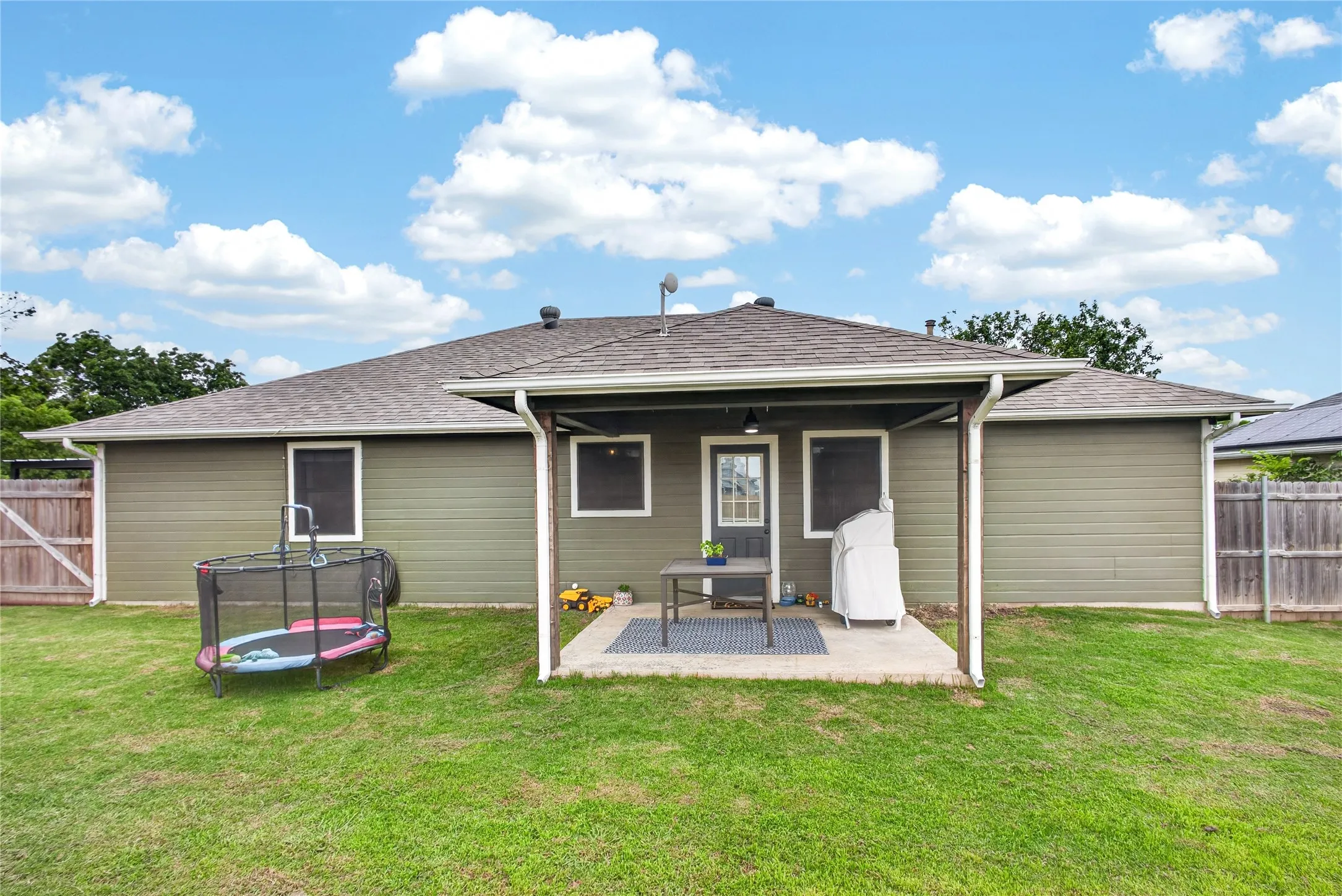 Expansive green lawn with a covered patio area and concrete slab
