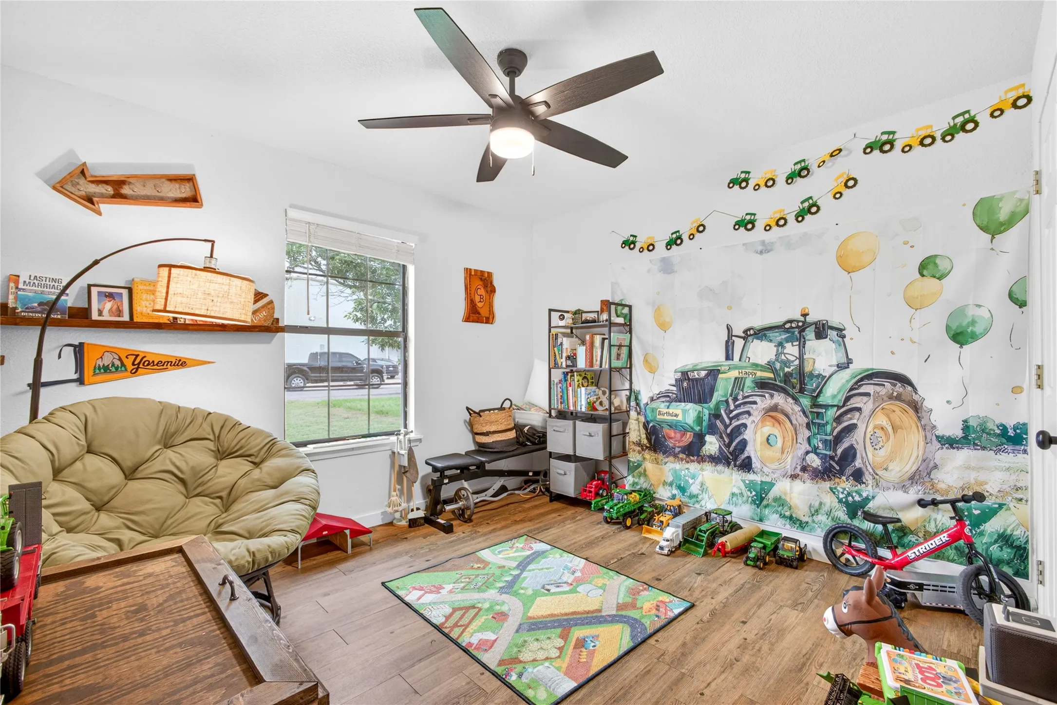 Bright room featuring wood-finish flooring, a ceiling fan with integrated lighting, and a window with blinds