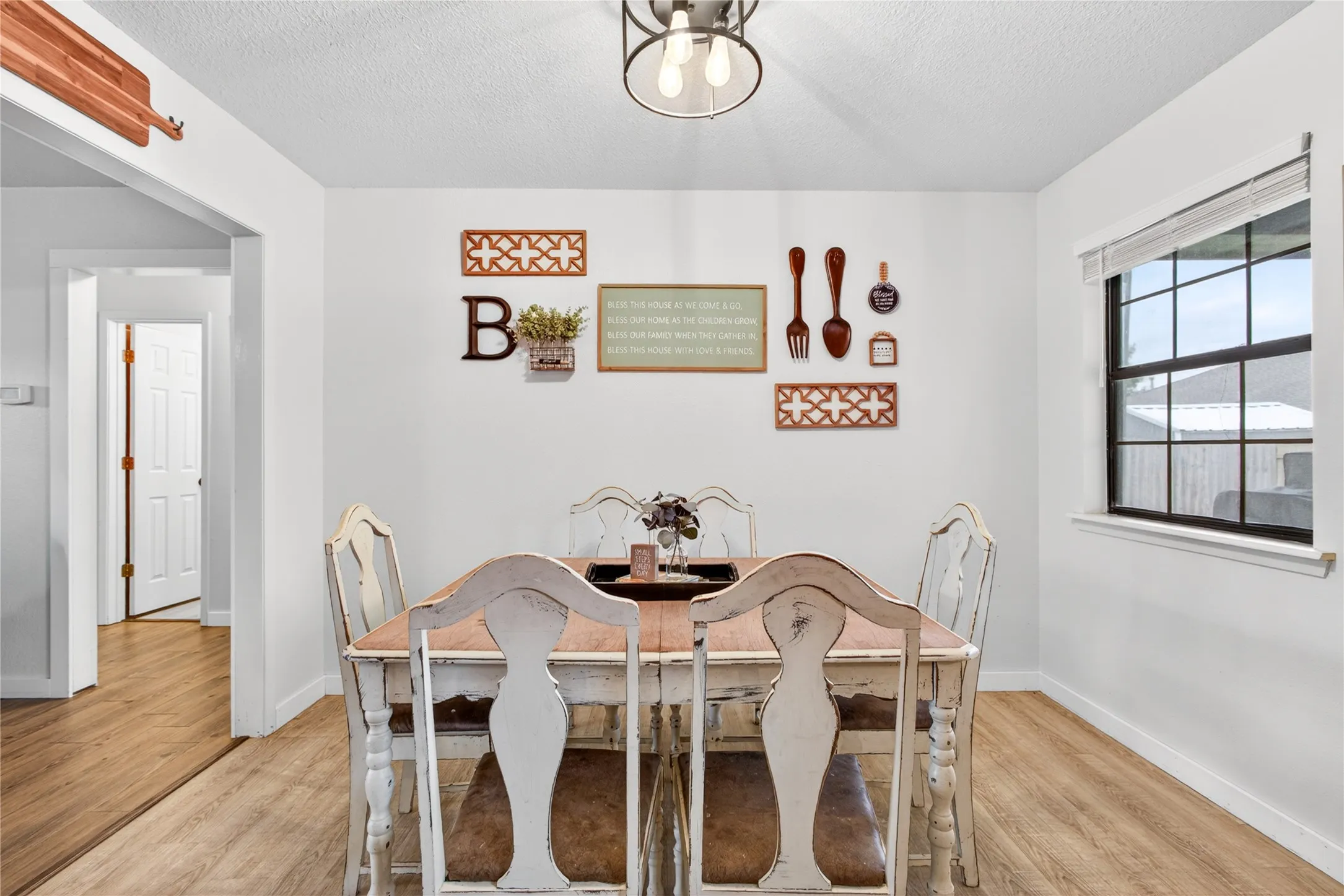 Dining area featuring wood-finish flooring, white walls, and a window with black trim