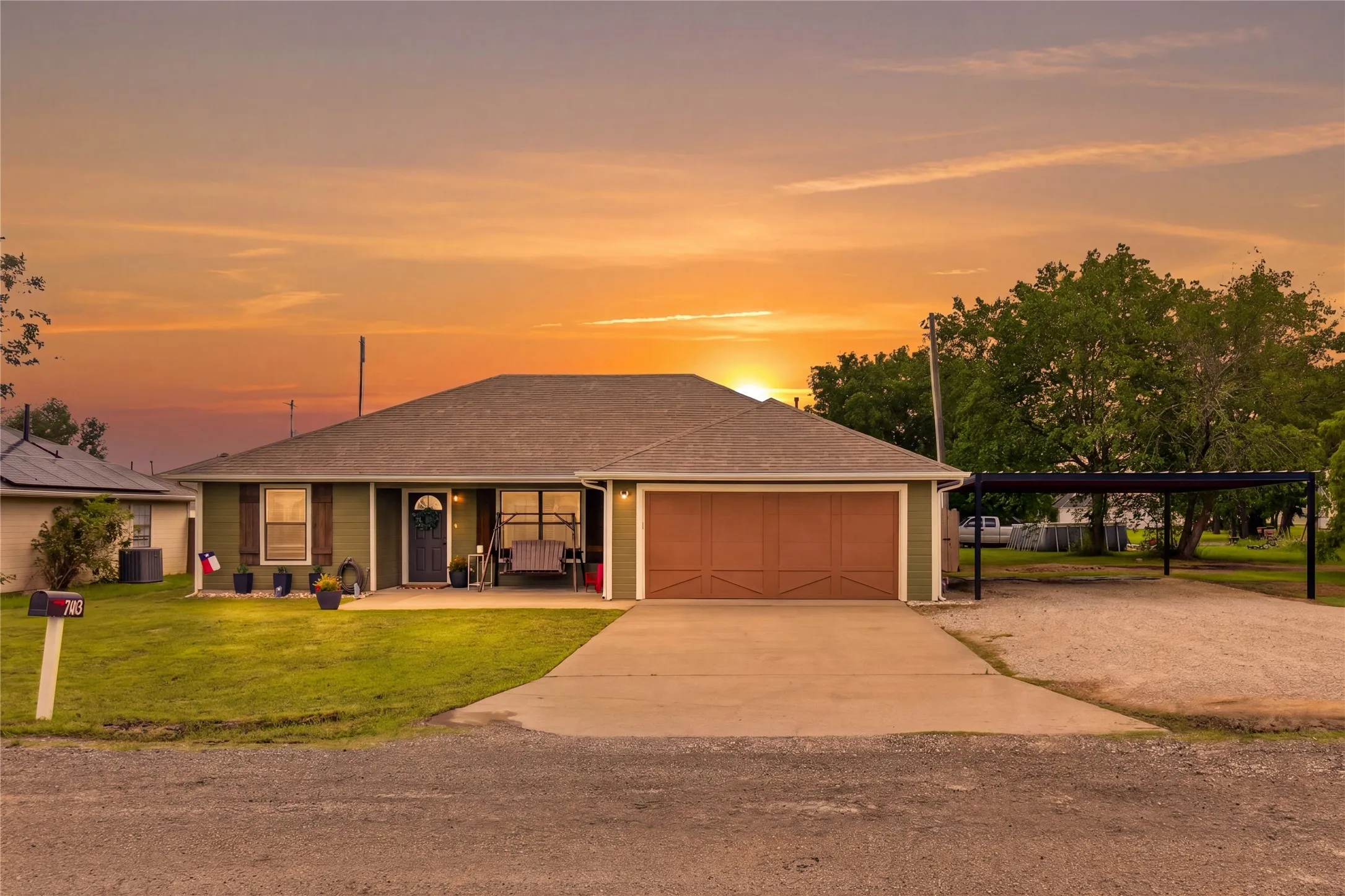 Ranch-style residence featuring a dark green exterior, an attached two-car garage with a brown door, and a concrete driveway