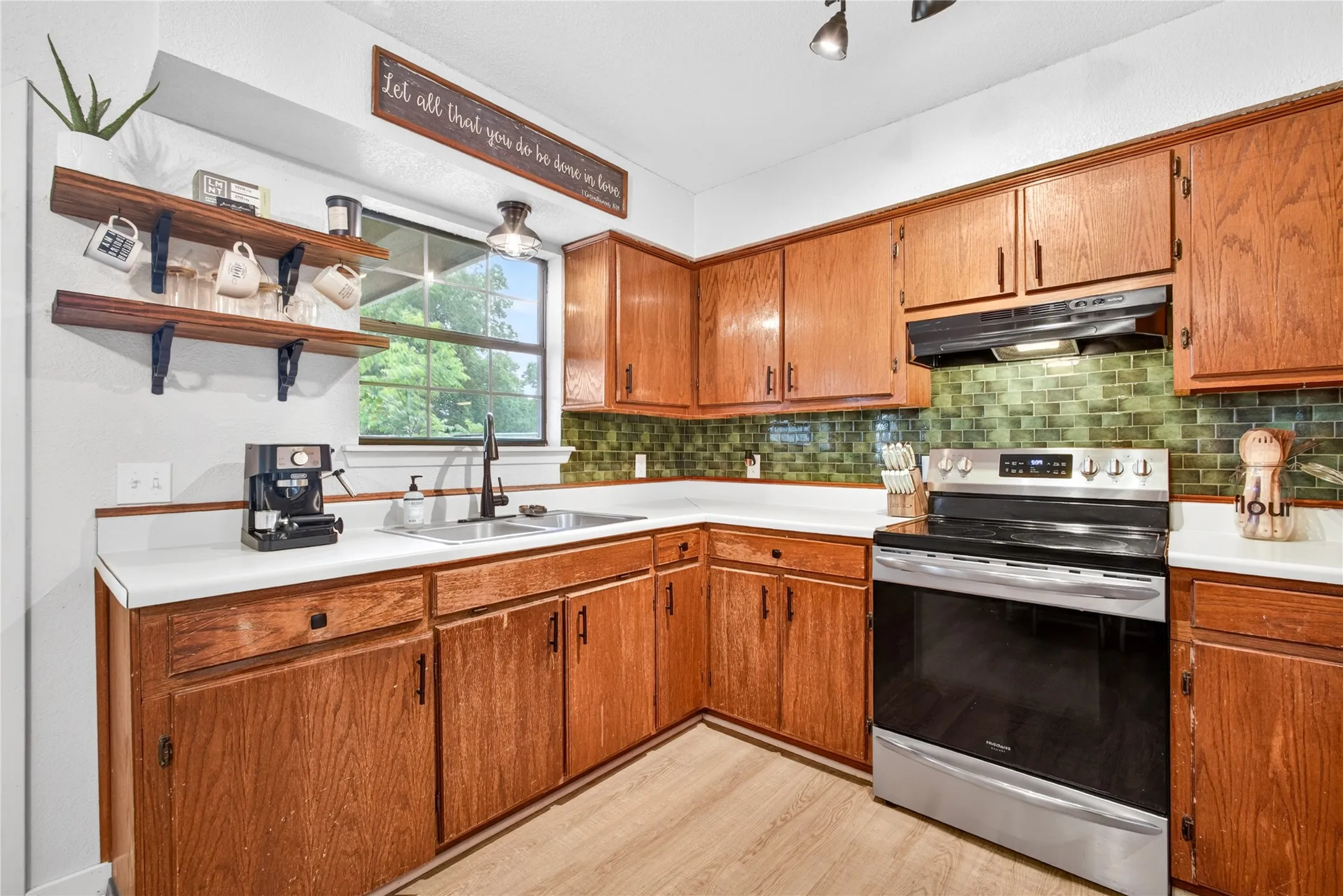 Kitchen featuring wood cabinetry, white countertops, a stainless steel range, and a green tile backsplash