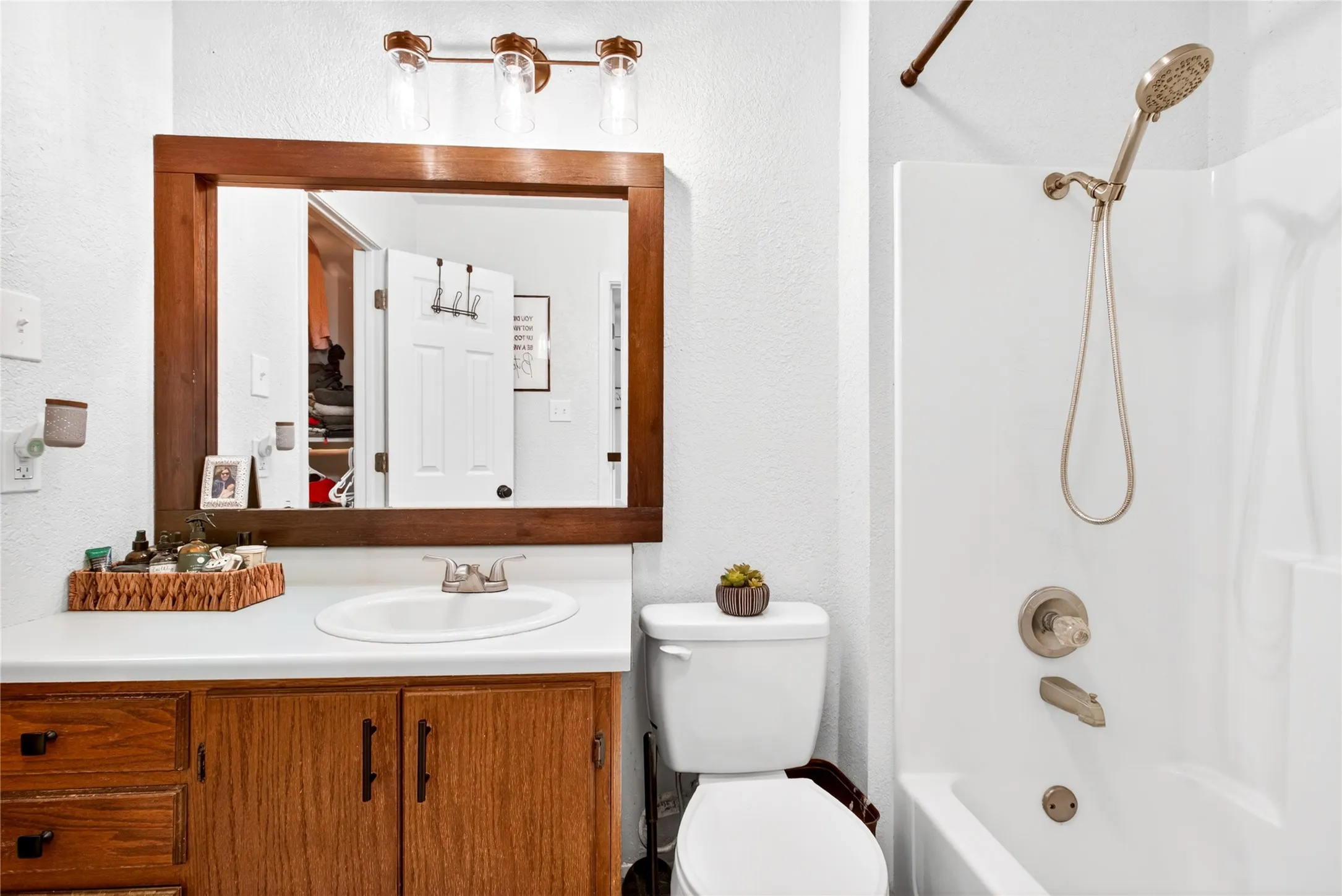 Bathroom vanity with wood-finish cabinetry, a white countertop, and a drop-in sink