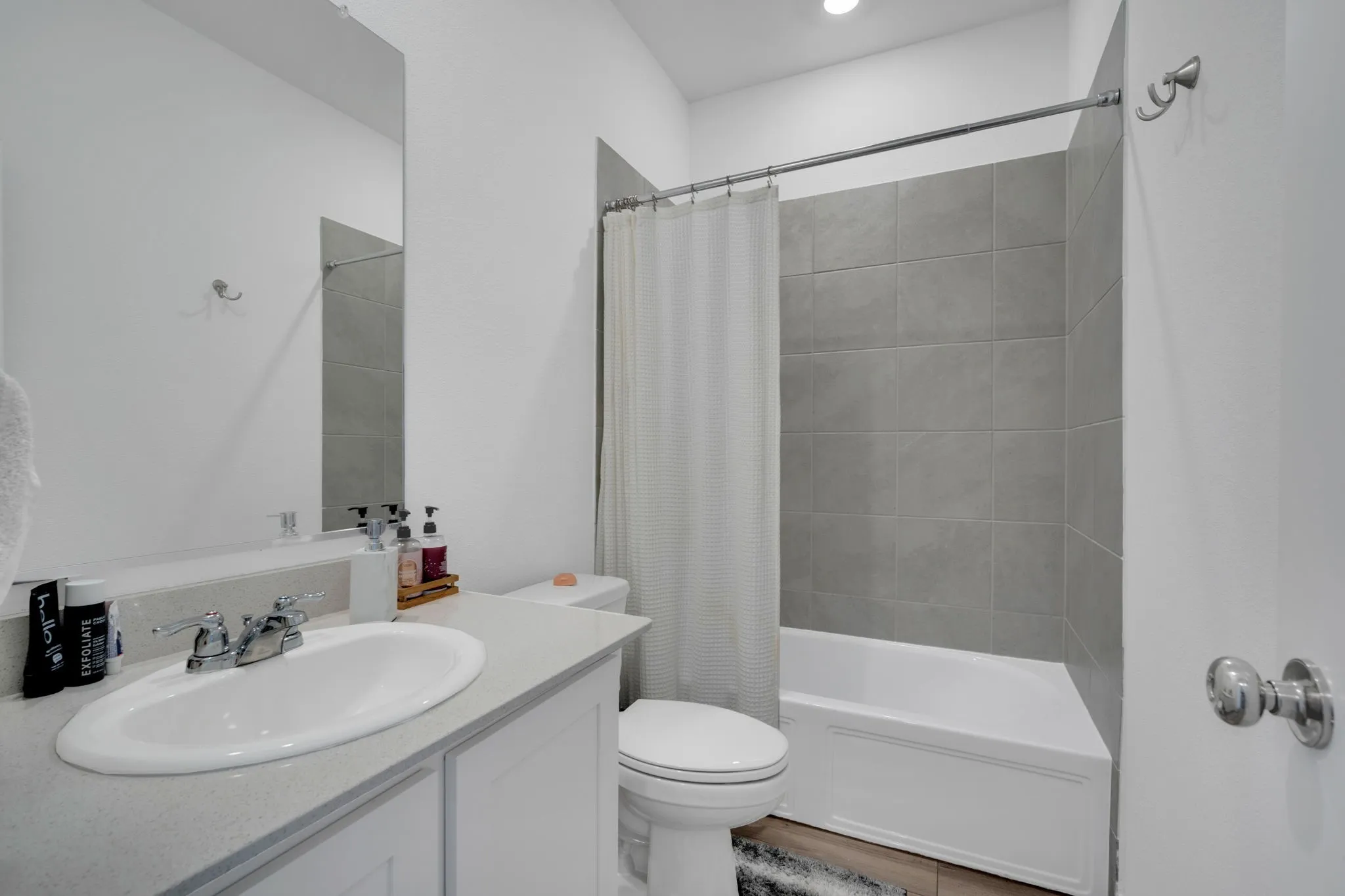 Contemporary bathroom featuring a white vanity with an undermount sink, chrome faucet, and expansive wall mirror