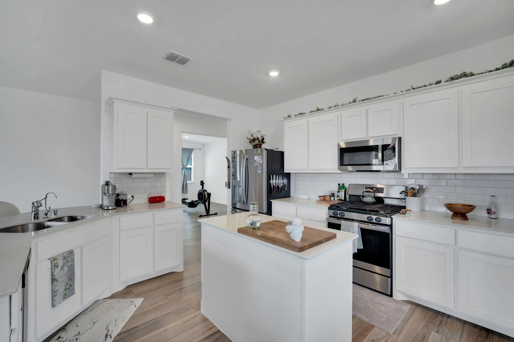 Modern kitchen featuring light wood-finish flooring, white cabinetry, and stainless steel appliances