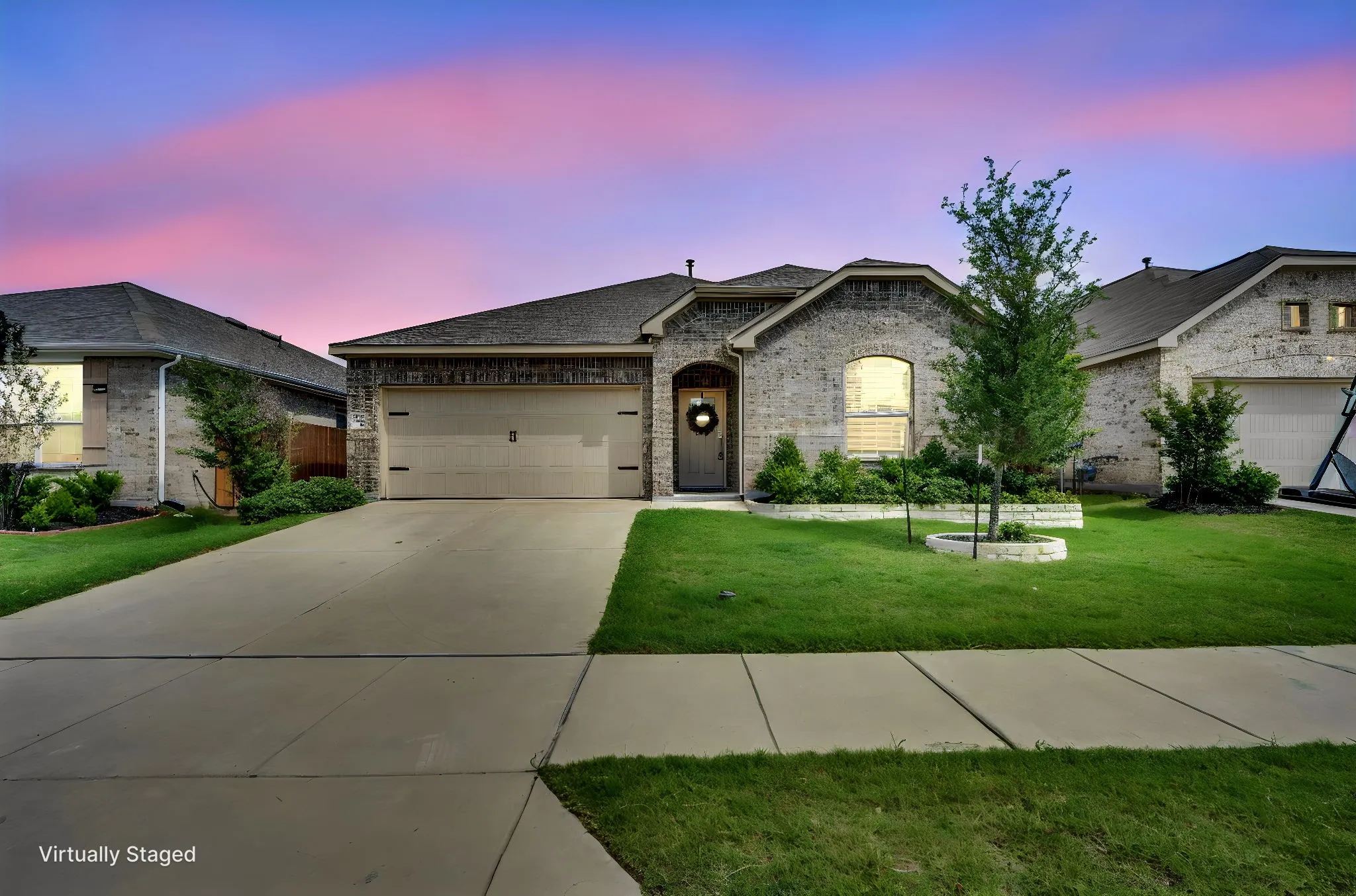 Brick veneer facade with an arched window, a two-car garage, and a concrete driveway