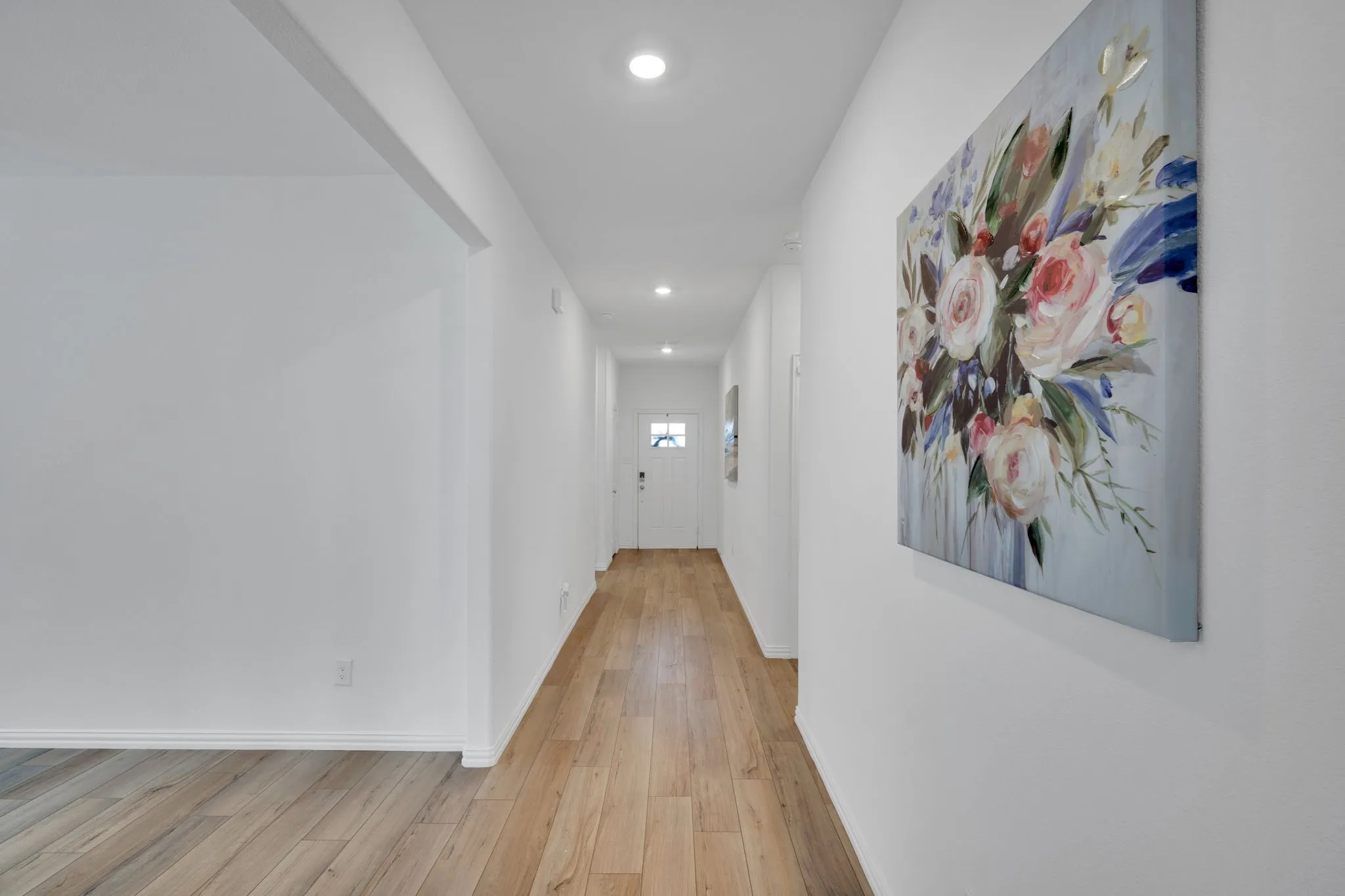 Expansive hallway featuring wood-finish flooring, recessed lighting, and a crisp white color palette