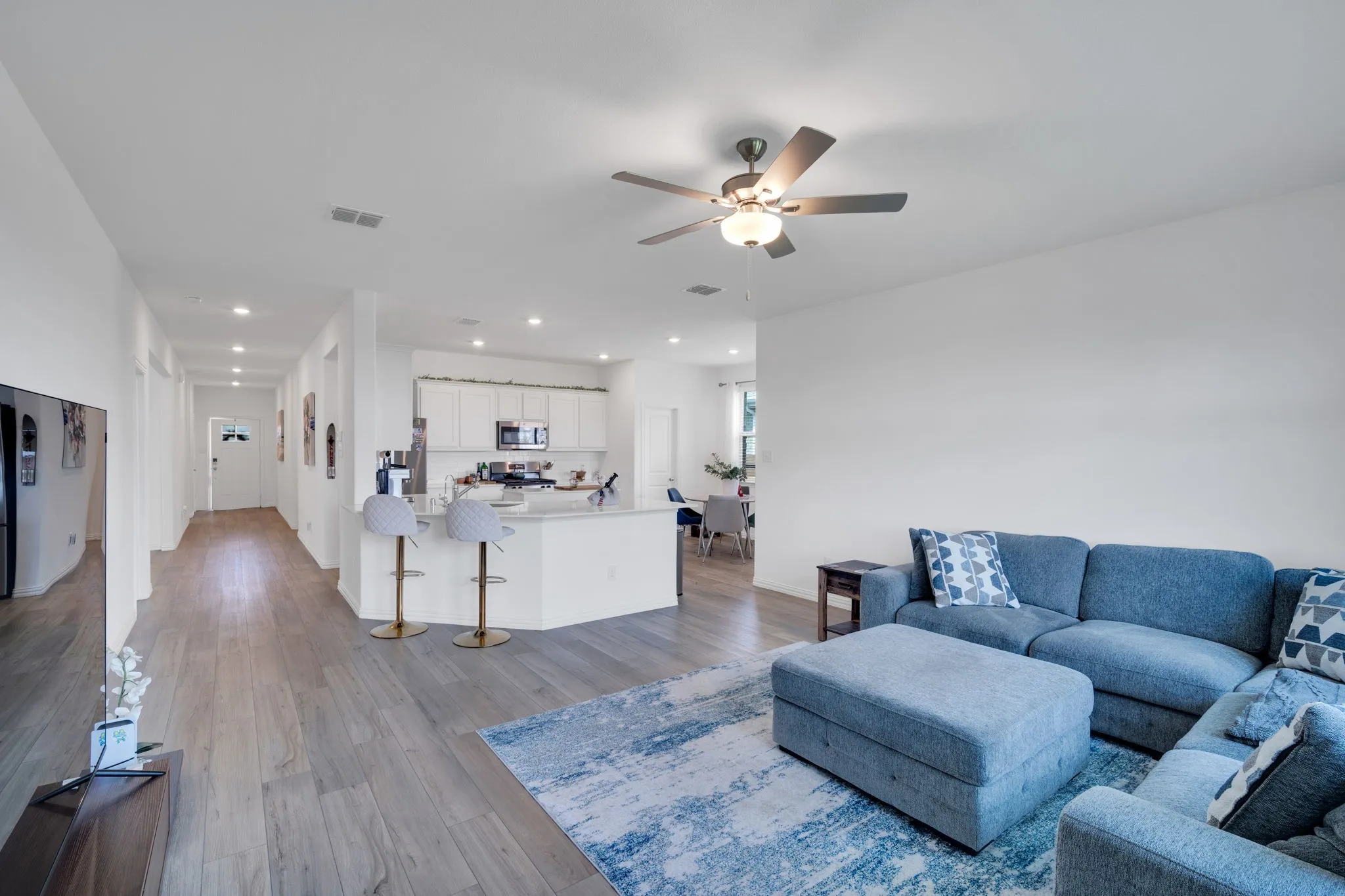 Expansive living space featuring wood-finish flooring and a ceiling fan with integrated lighting