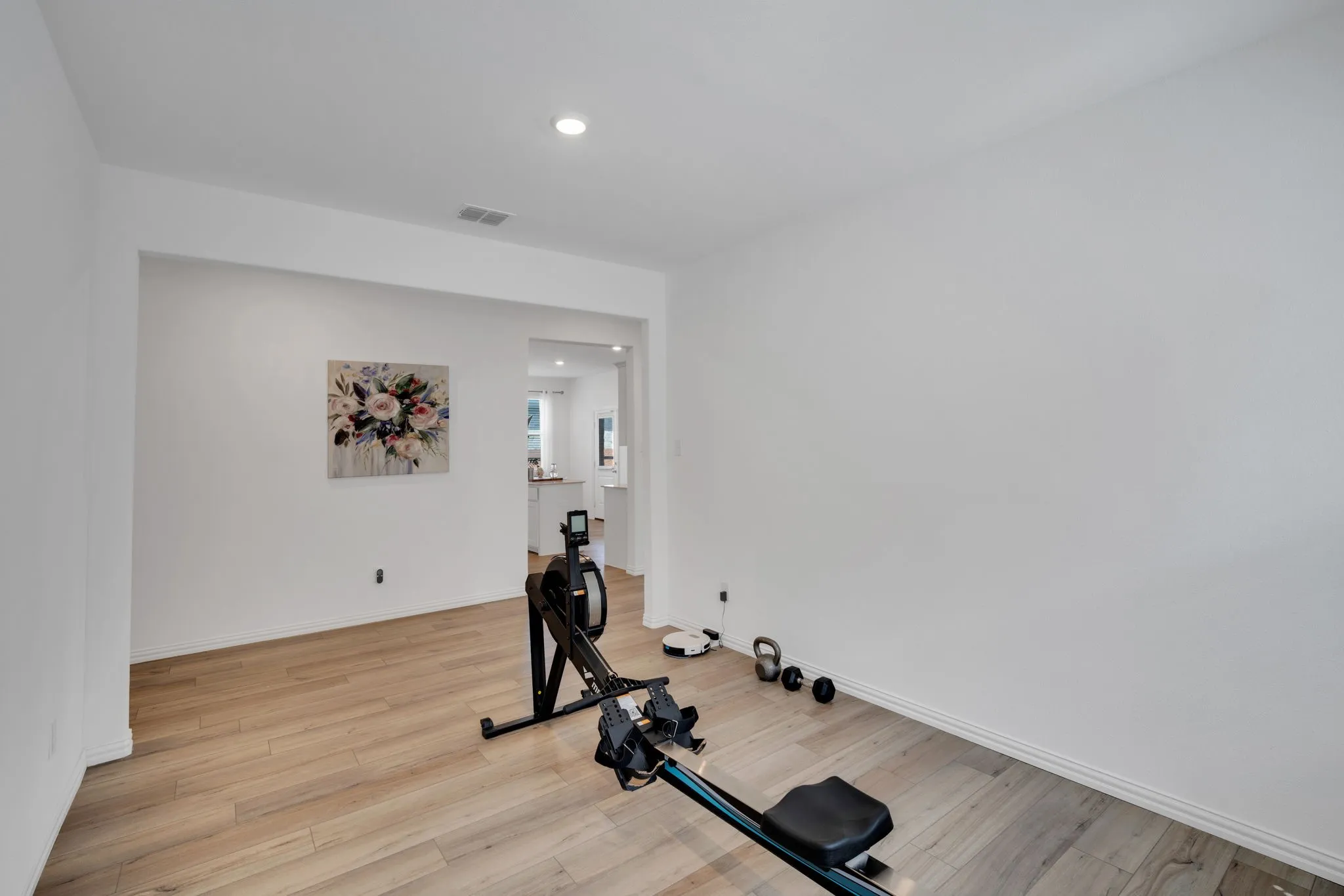 Spacious room featuring light wood-finish flooring, recessed lighting, and crisp white walls