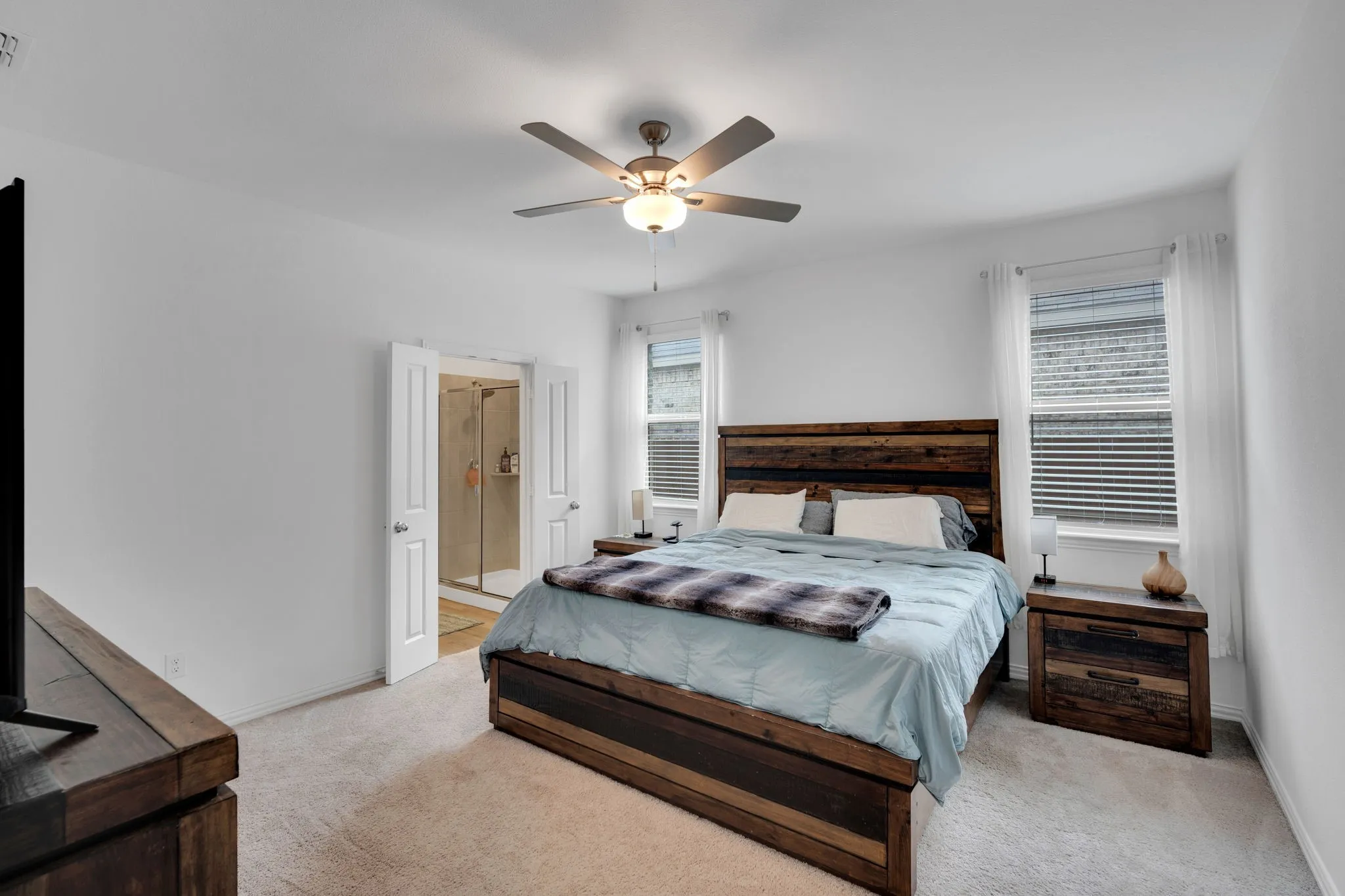 Carpeted sleeping area with white walls and a ceiling fan with integrated lighting