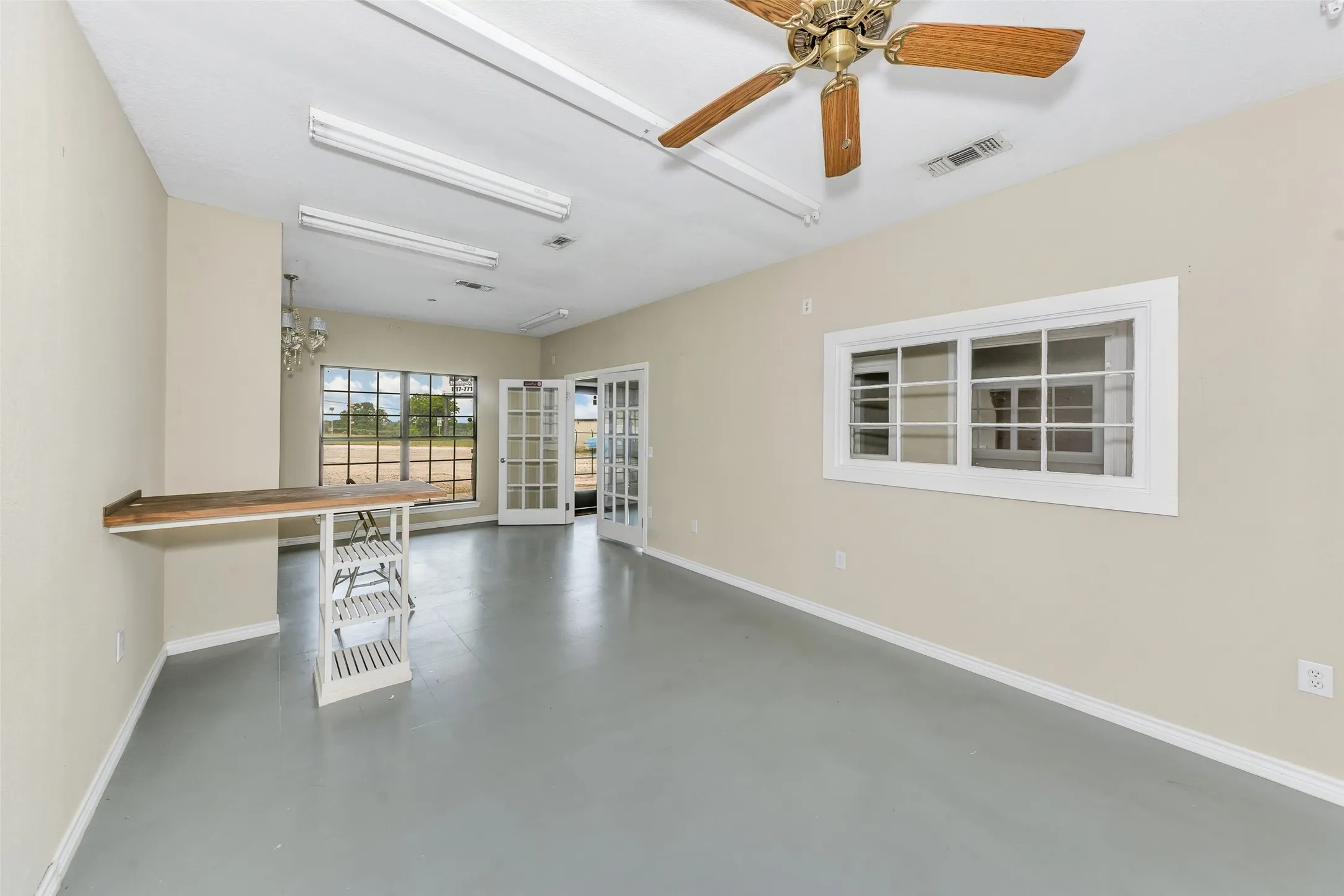 Spacious room featuring light neutral wall paint and a painted concrete floor