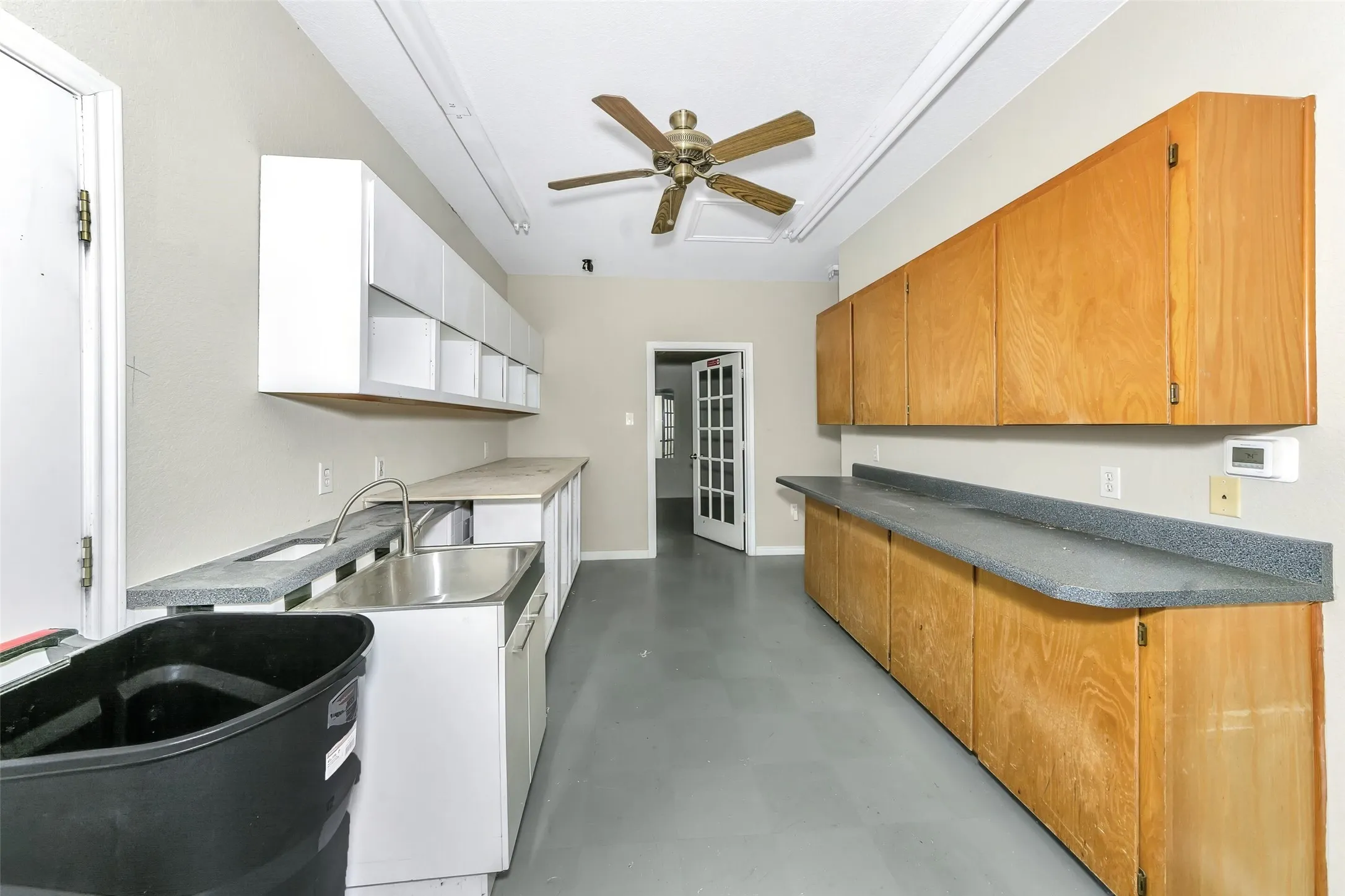 Spacious utility room featuring extensive white and wood-finish cabinetry, a large stainless steel utility sink, and ample countertop space