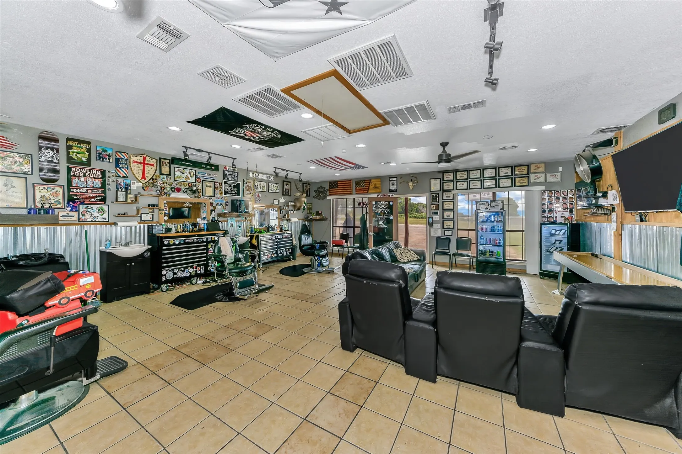 Spacious interior with neutral tile flooring, window coverage along the far wall, and track lighting