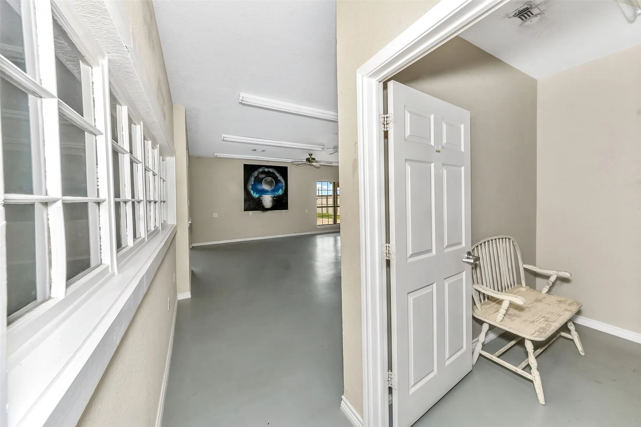Expansive interior space featuring light gray flooring, neutral wall tones, and extensive window light