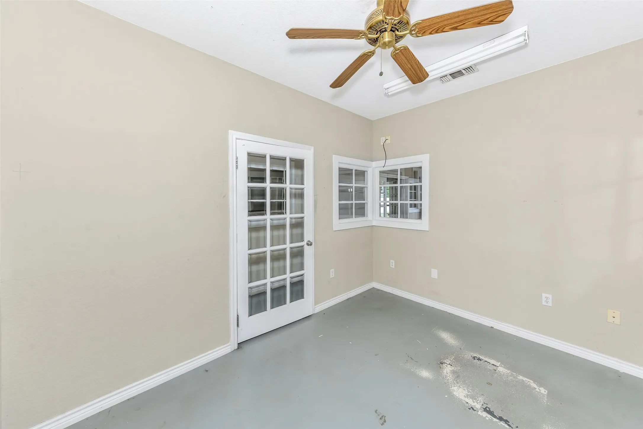 Room featuring a ceiling fan, corner windows with white framing, and a white paneled door