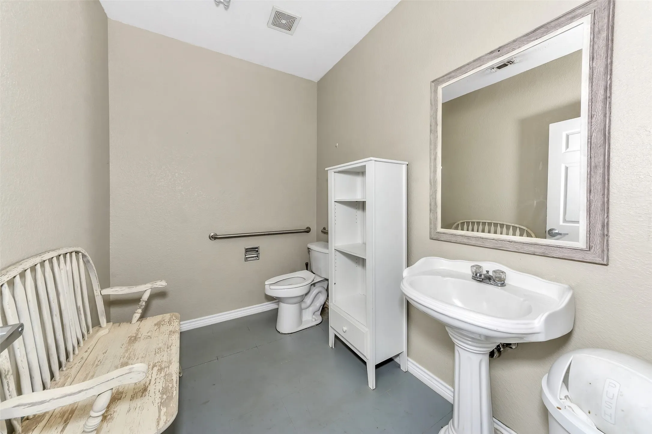 Pedestal sink with chrome fixtures, framed mirror, built-in shelving, white toilet, and grab bar