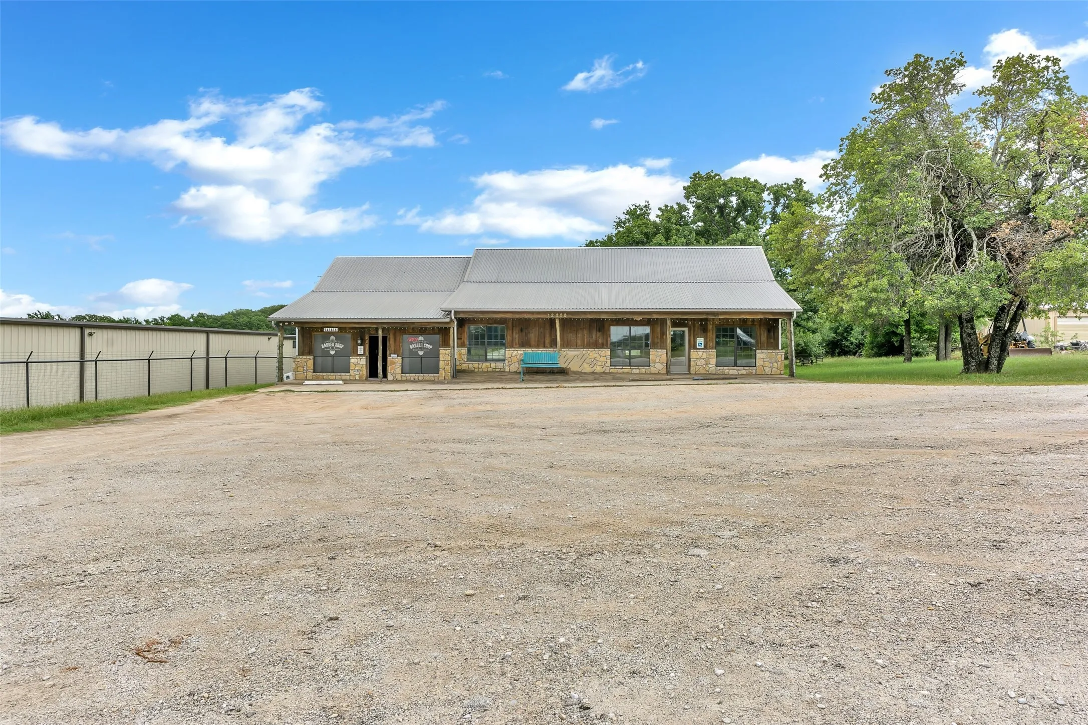 Commercial building with a metal roof, stone and wood siding, and an expansive gravel parking lot