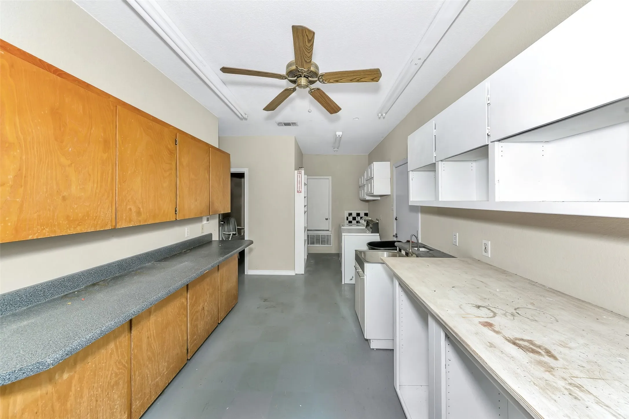 Utility space featuring extensive wood-finish cabinetry, solid surface countertops, and an integrated stainless steel sink